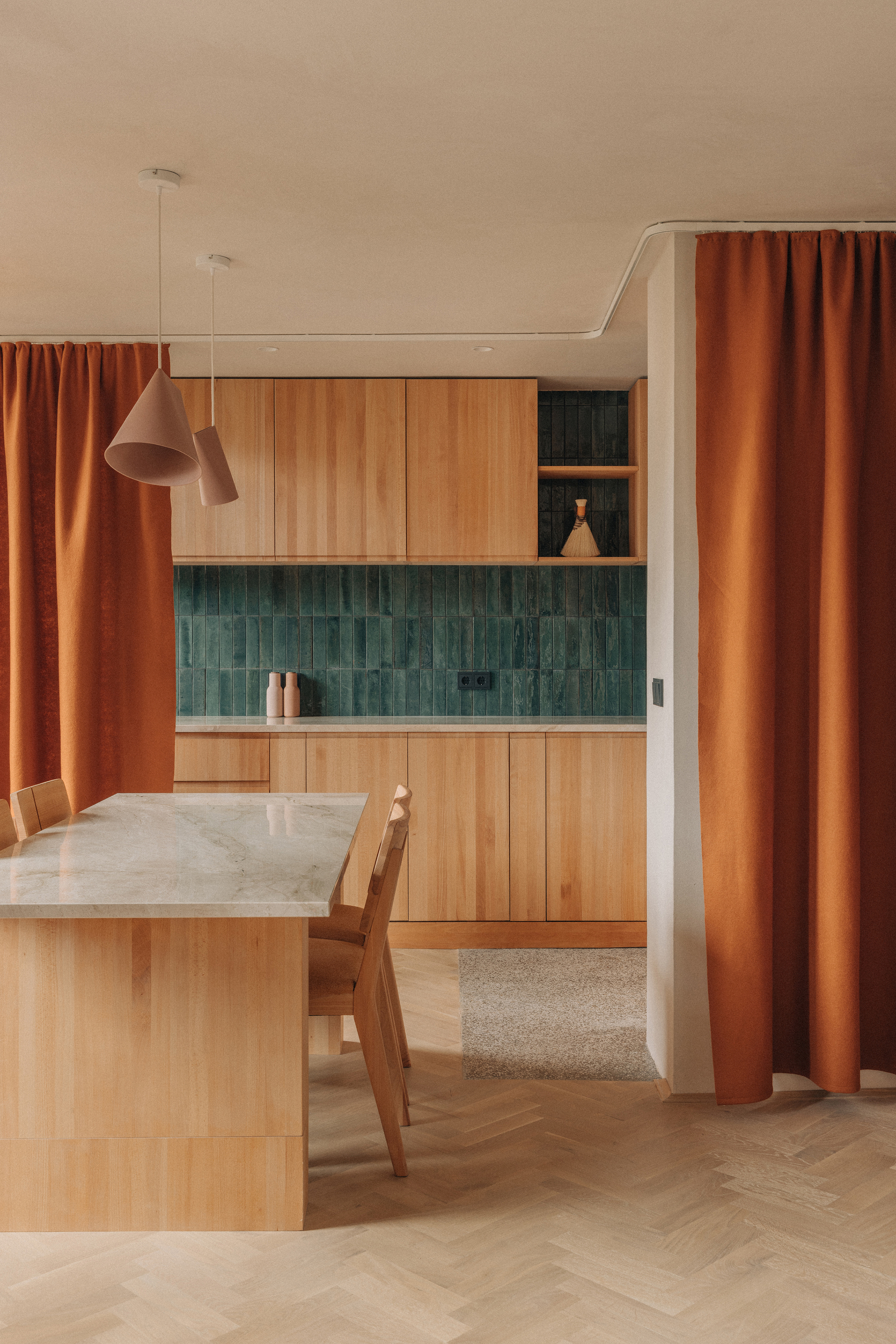 Dining area with pendant light and green tile backsplash framed by orange curtain panels