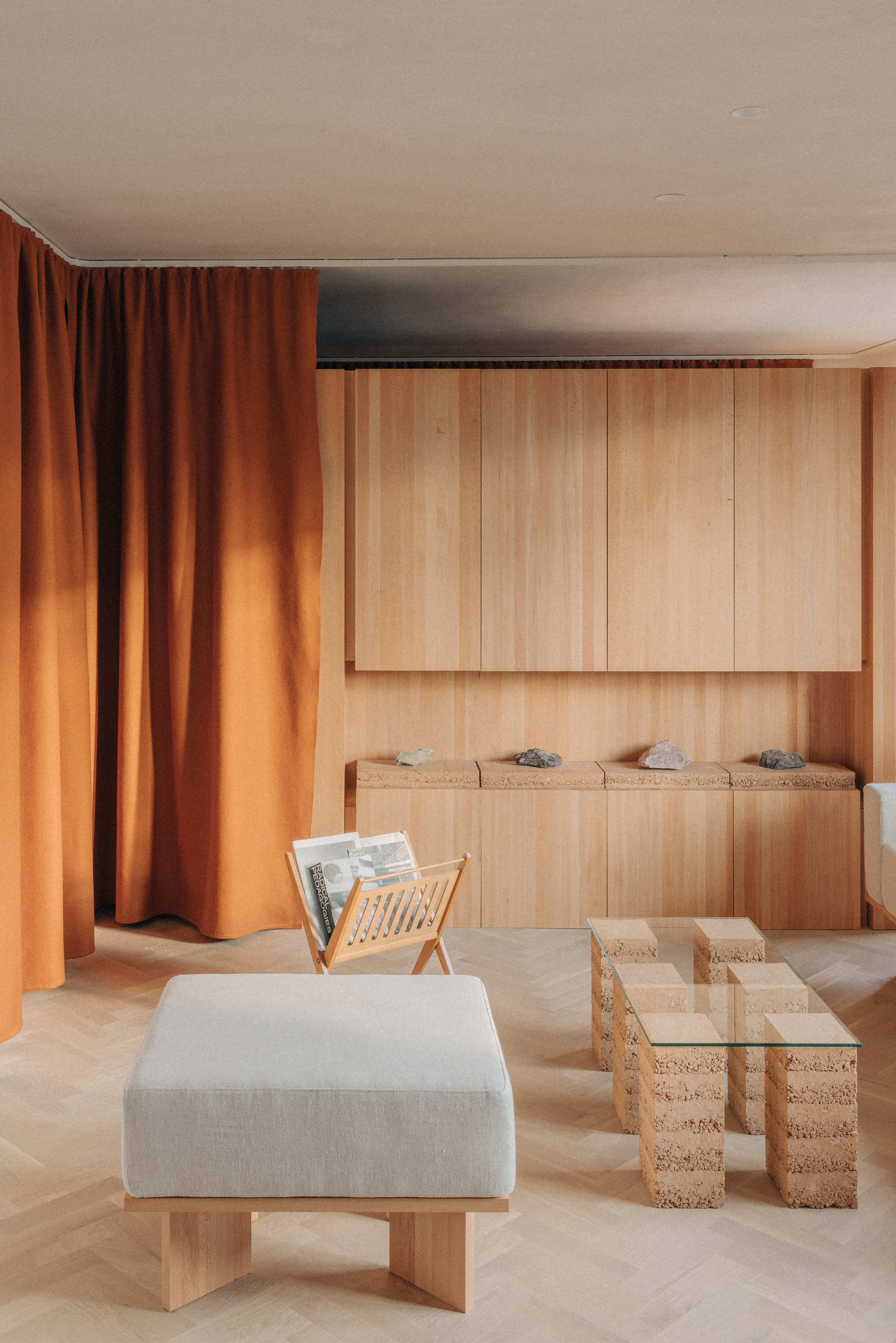 Interior with vertical timber paneling, built-in bench seating, and cork block tables beneath a recessed ceiling