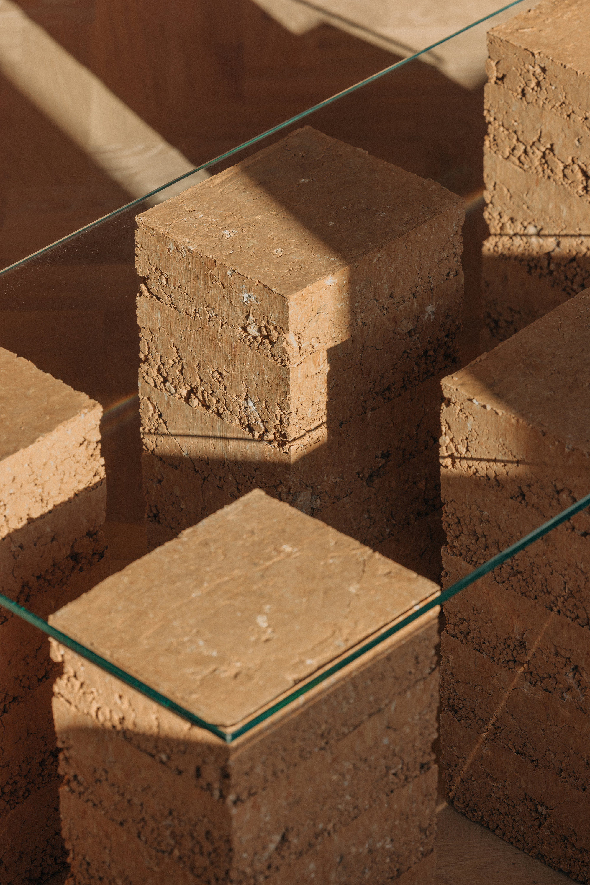 Close-up of stacked cork blocks topped with clear glass under direct sunlight