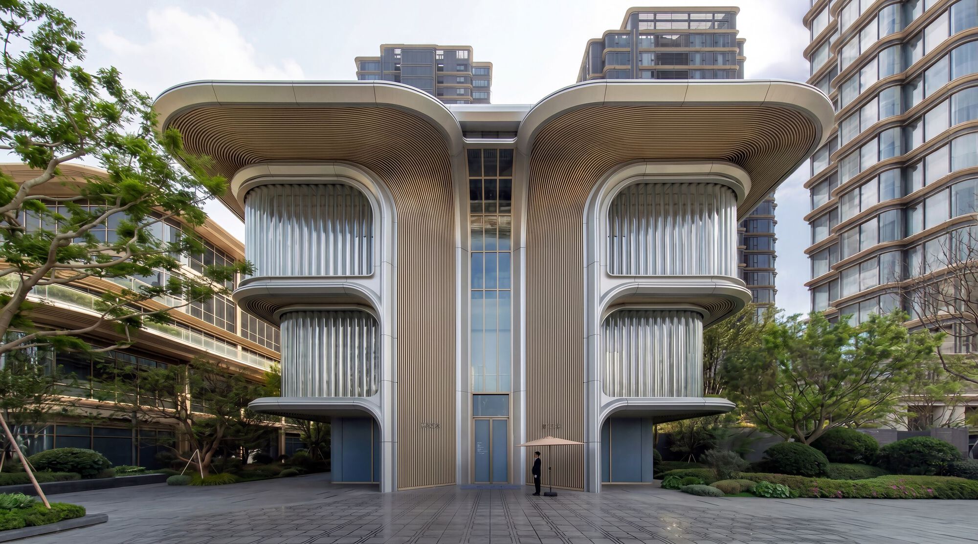 Twin vertical louvered facades with ribbed soffits flanking a glazed entry volume at dusk