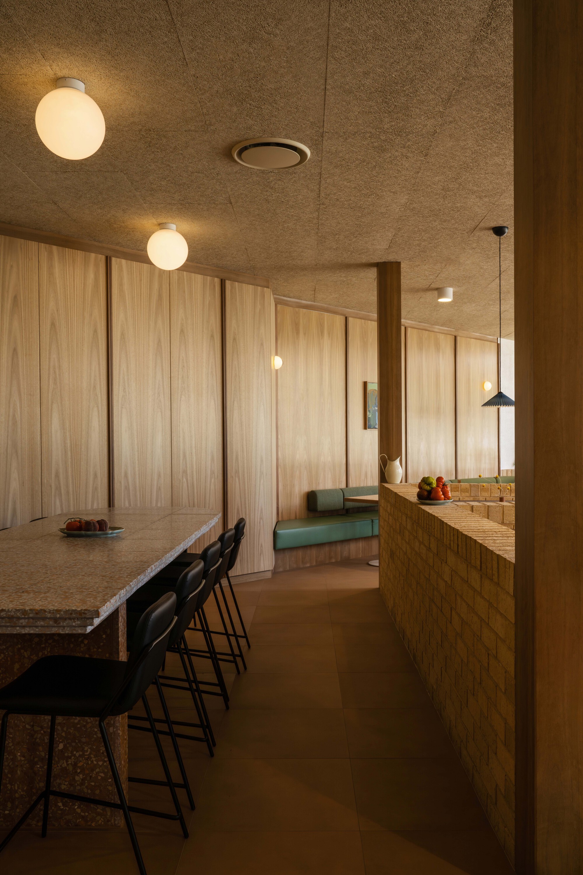 Interior dining area with cork ceiling panels, globe pendant lights, and vertical timber wall cladding