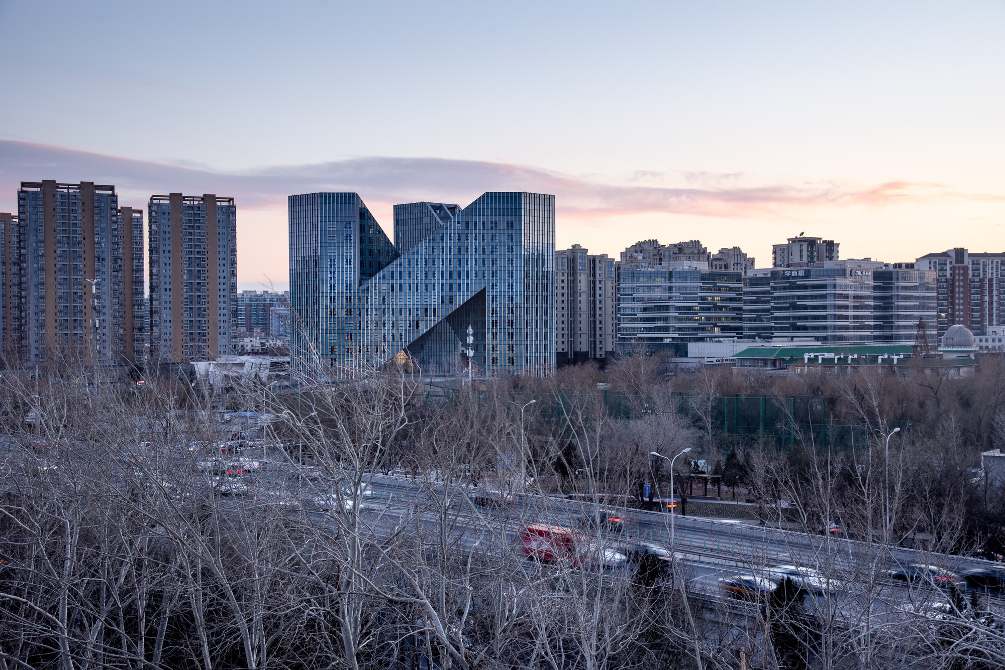 Distant view of the angular towers rising above leafless trees at dusk