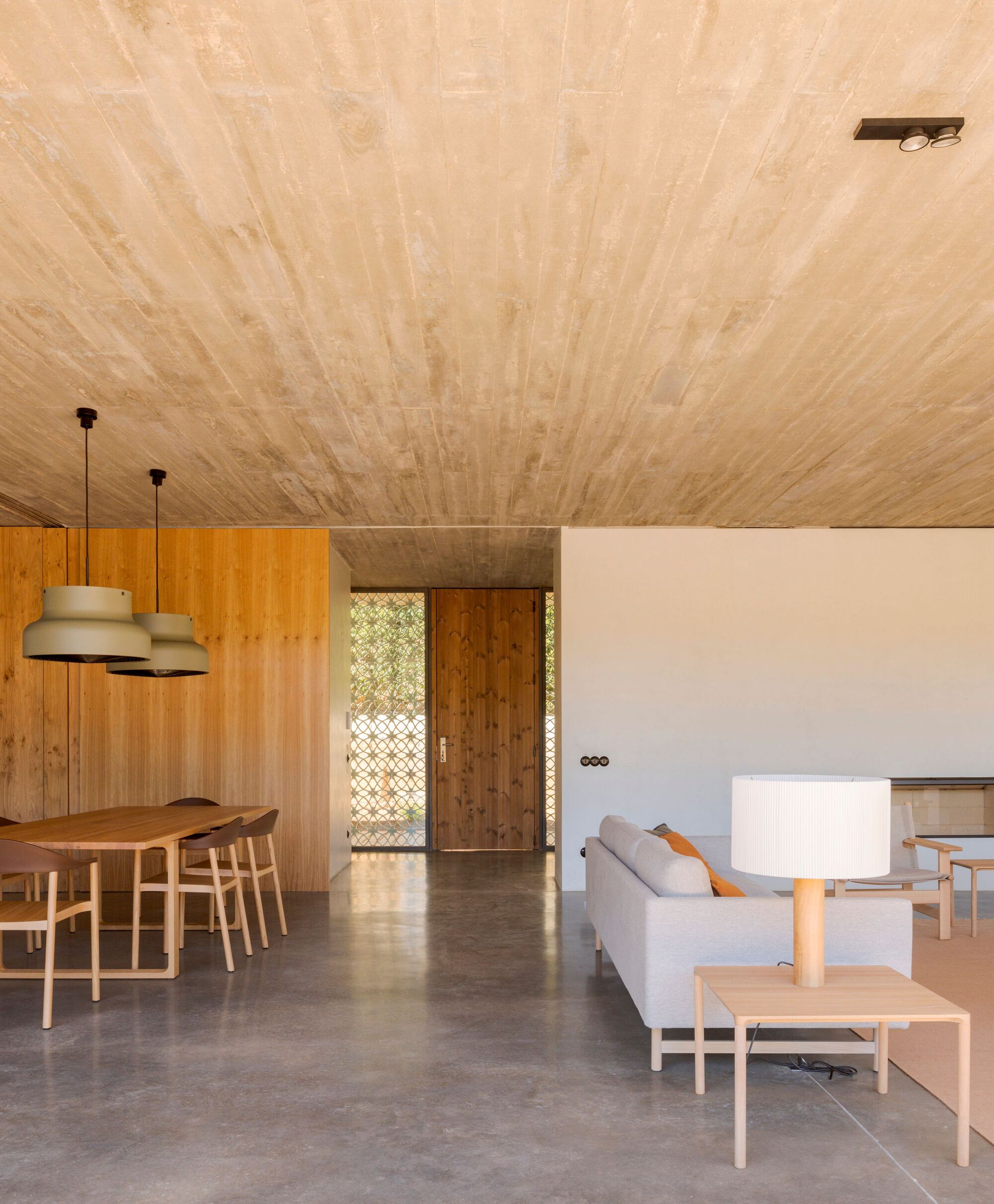 Open-plan living space with exposed timber plank ceiling and polished concrete floor