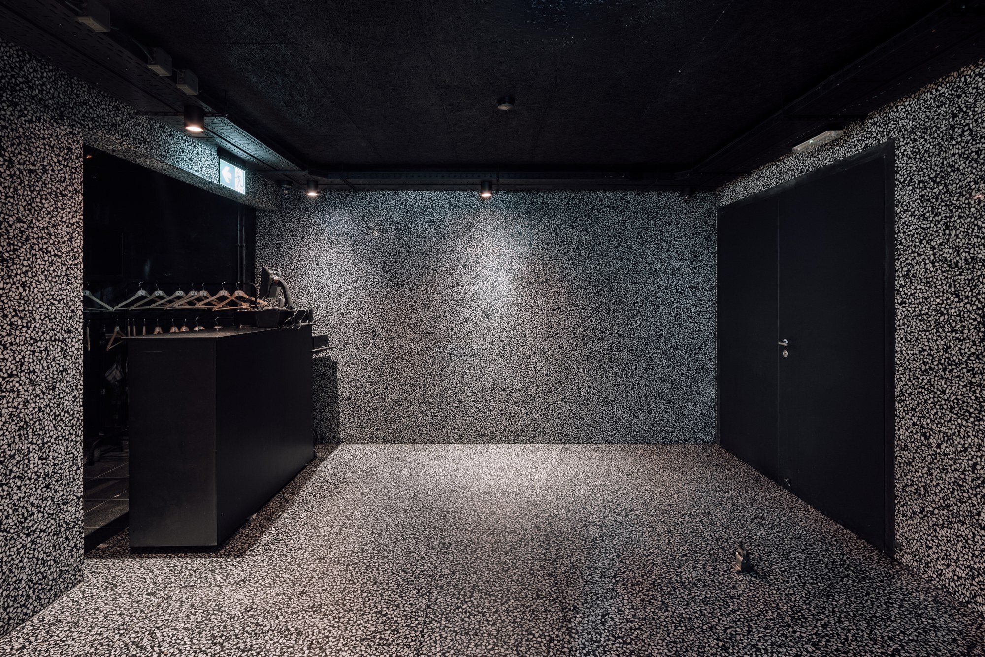 Black-walled room with terrazzo flooring and walls extending to ceiling under artificial light
