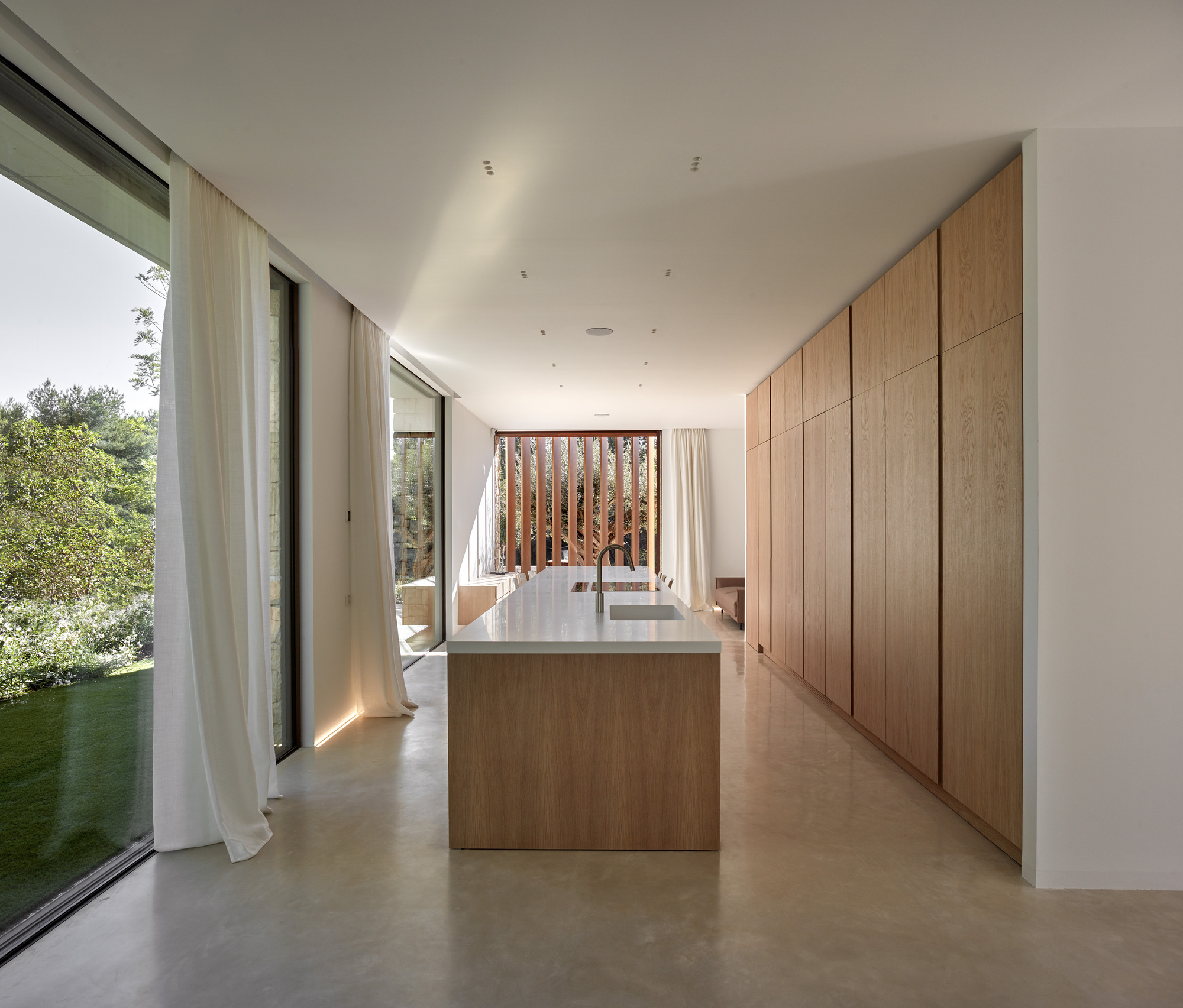 Kitchen with oak island and full-height cabinetry opening to a vertical timber screen beyond