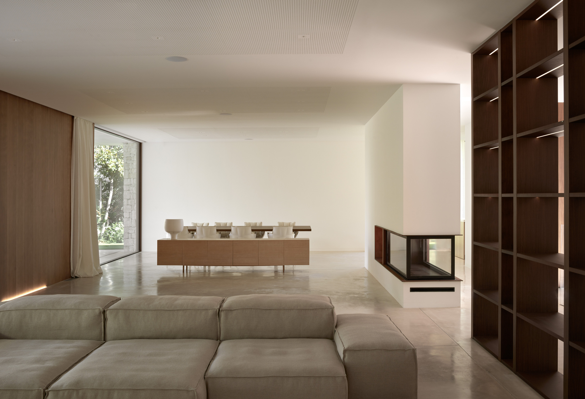 Living room with white fireplace insert and walnut shelving wall overlooking the dining area