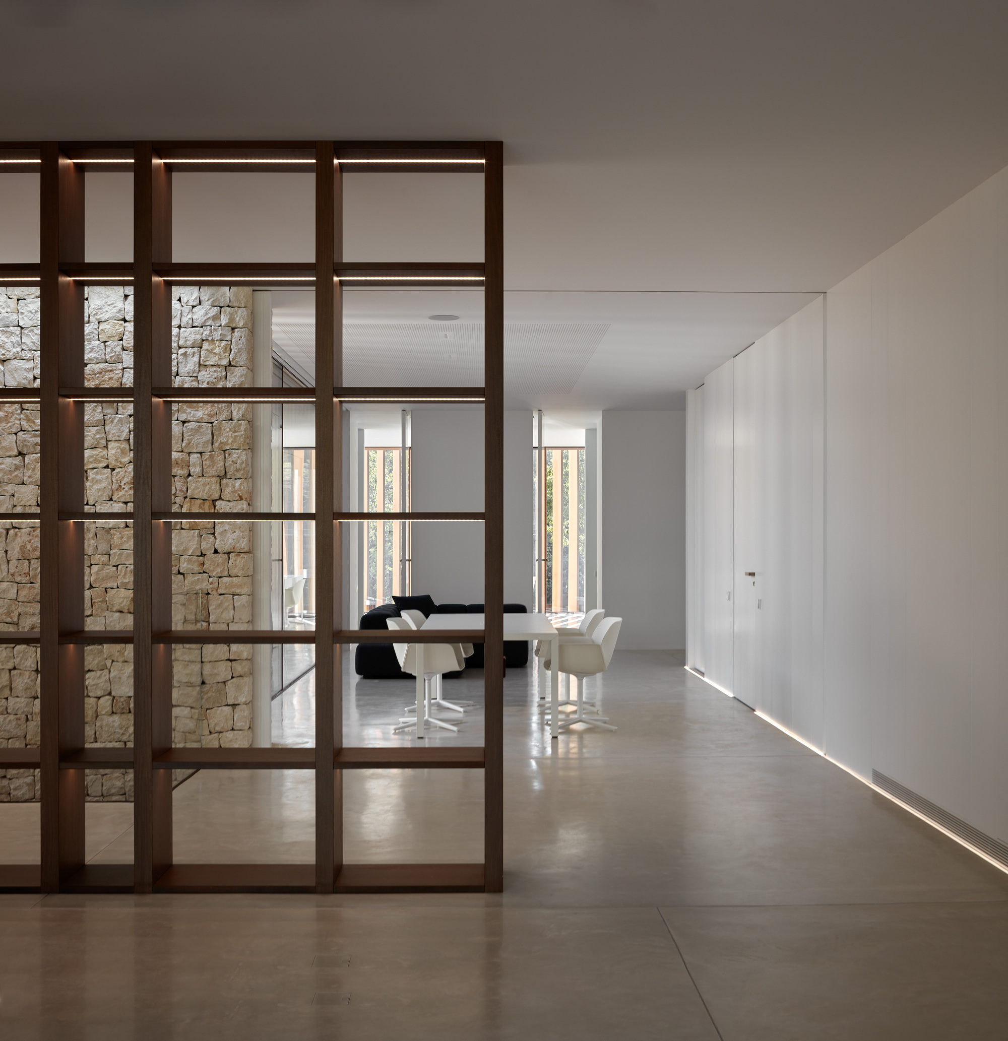 Dark timber framed glass partition dividing the corridor from the dining room with concealed floor lighting