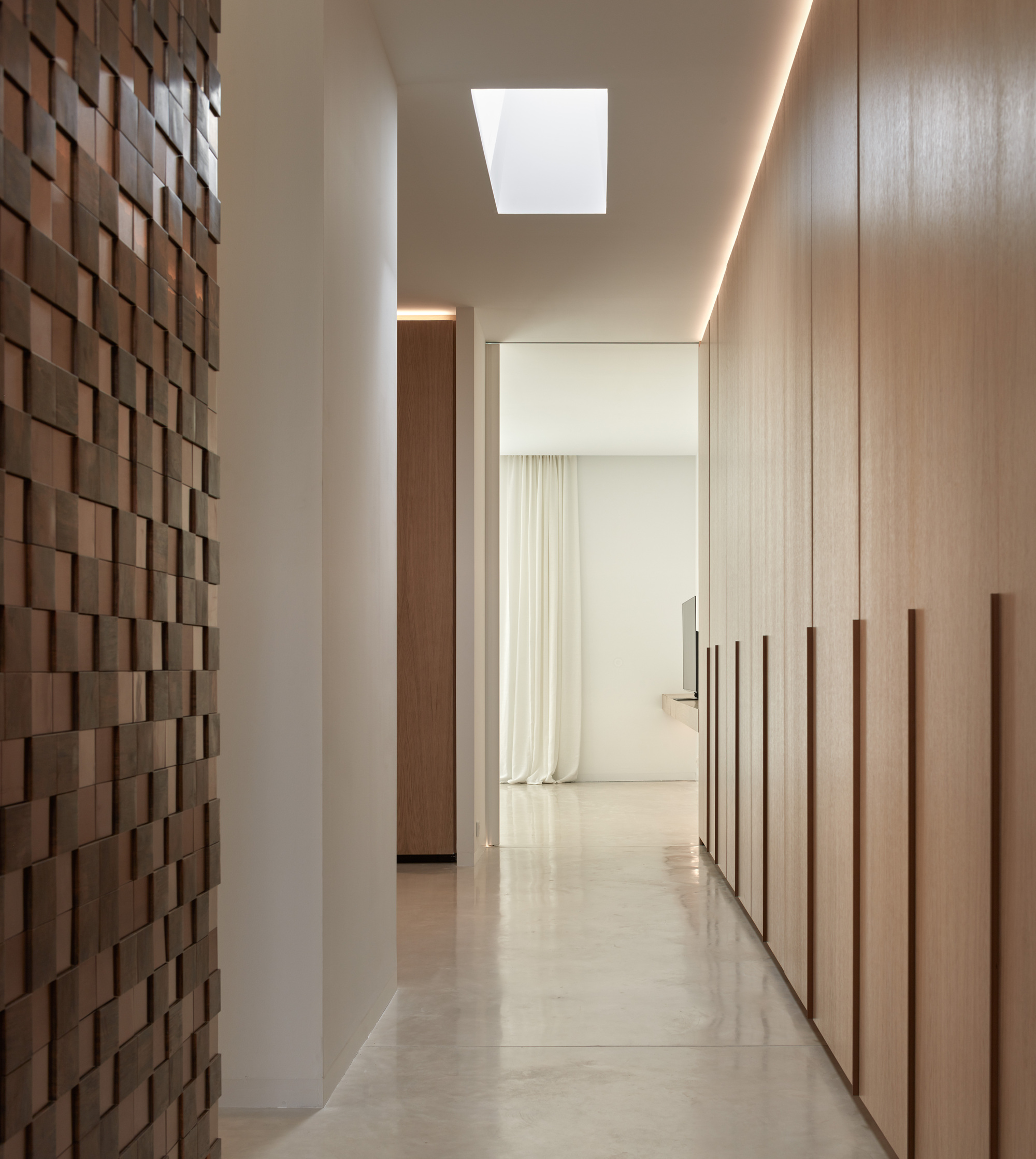 Corridor with terracotta tile feature wall, wood-clad storage and skylight overhead