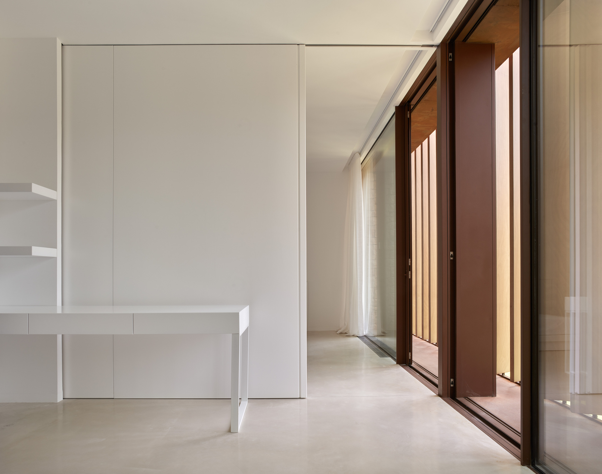 Interior space with sliding wood-framed glazed doors and white built-in desk