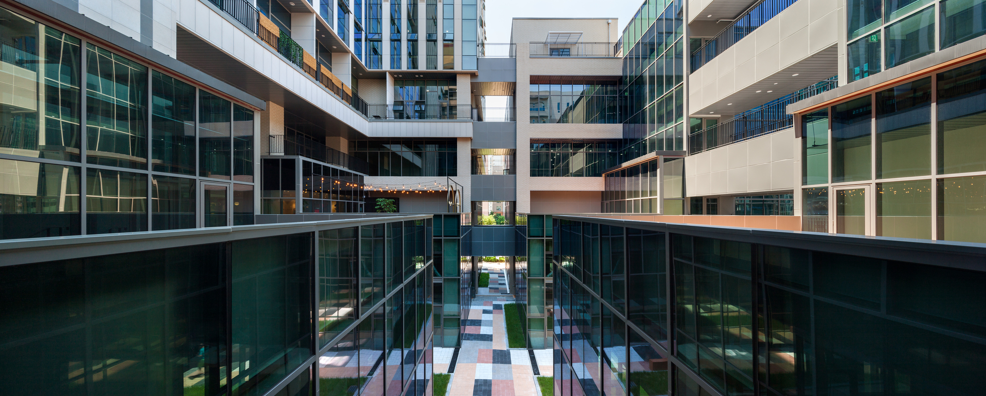 Glazed interior courtyard with bridges spanning between buildings at dusk with illuminated upper levels