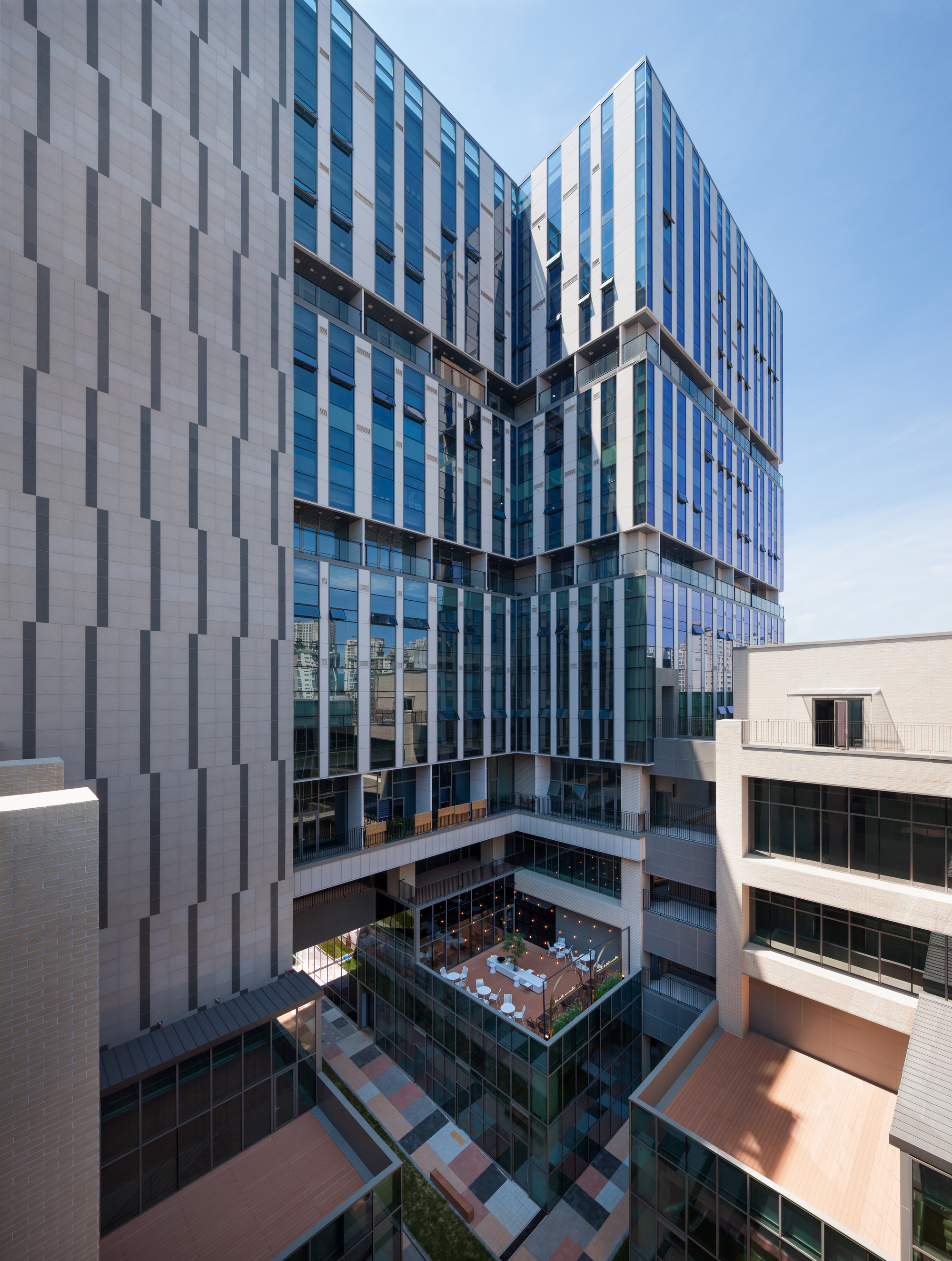 Corner view of the stacked glass and panel facades with terraced massing overlooking the interior courtyard in daylight