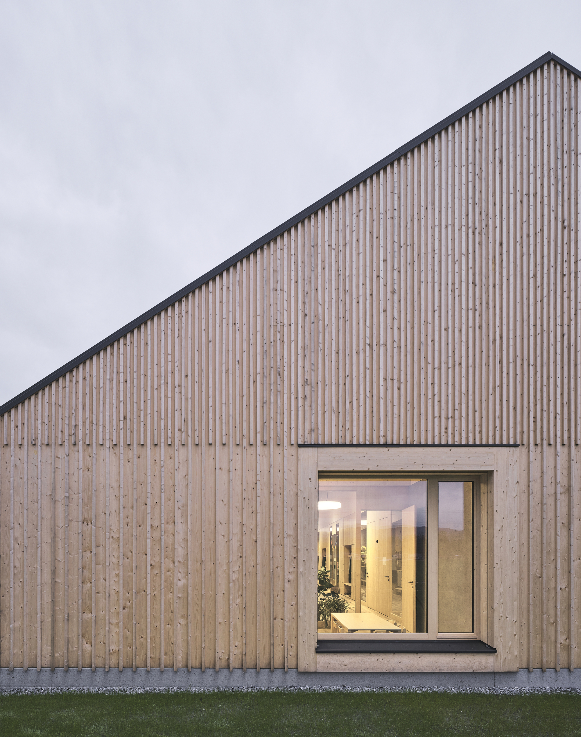 Close view of the vertical wood slat cladding and concrete-framed glazed opening