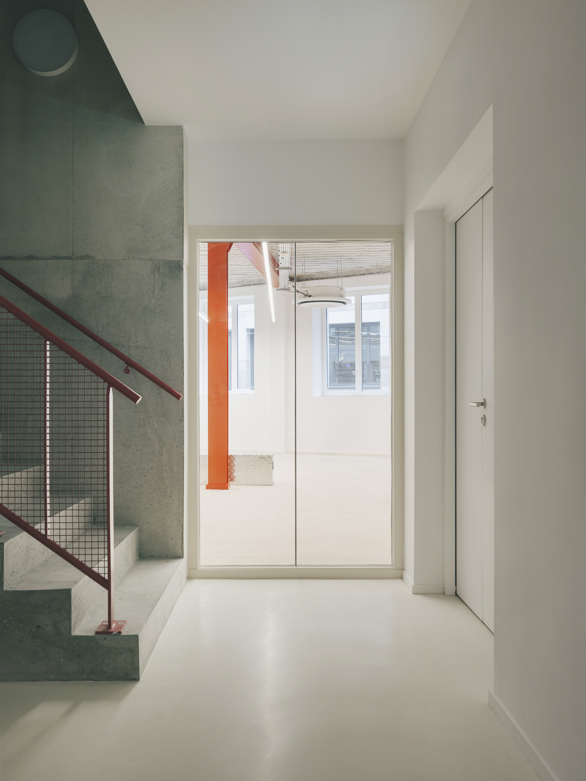 White floor hallway with concrete stair visible through doorway and circular ceiling light above