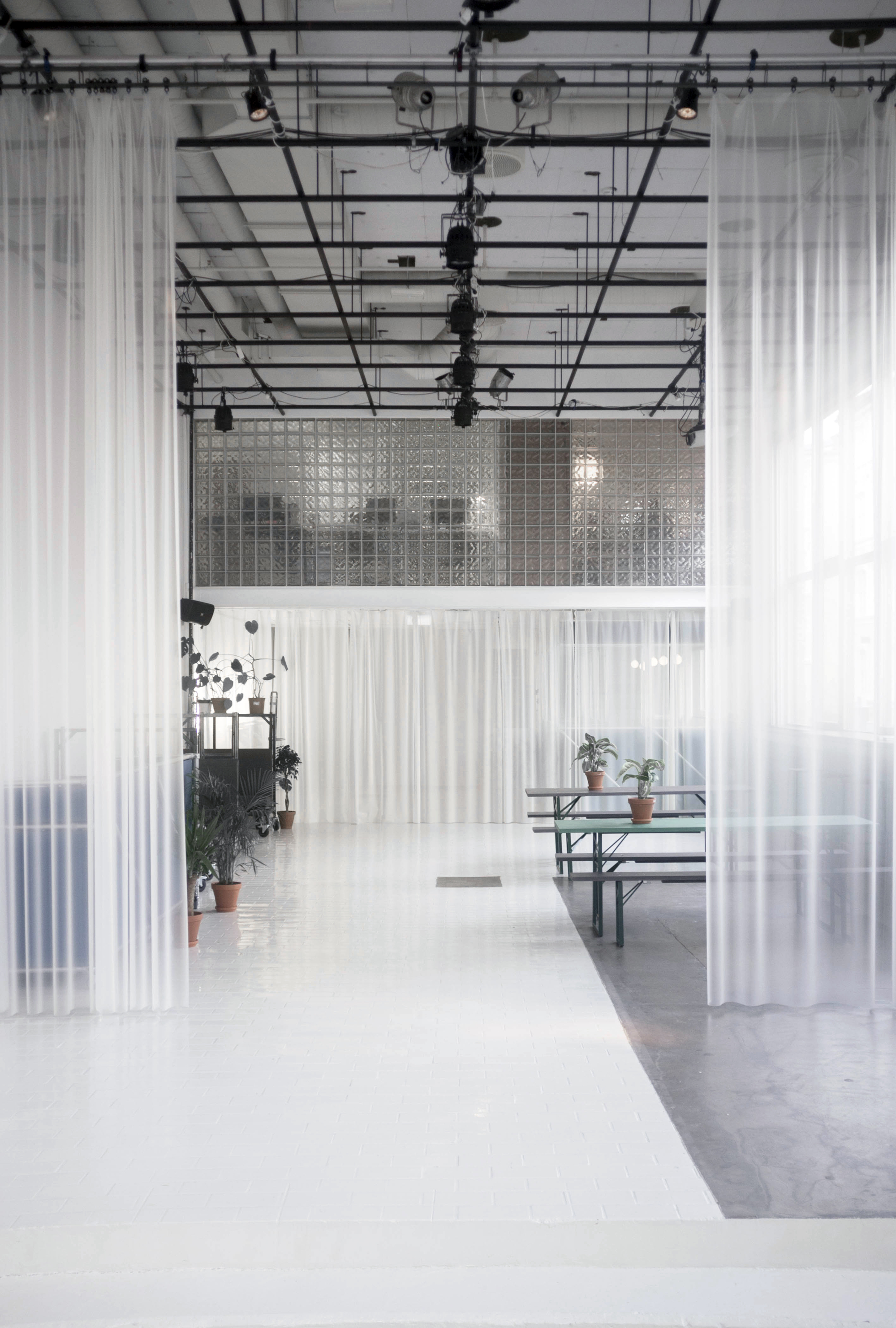 Corridor with translucent fabric partitions hanging from the industrial ceiling structure and lighting rig