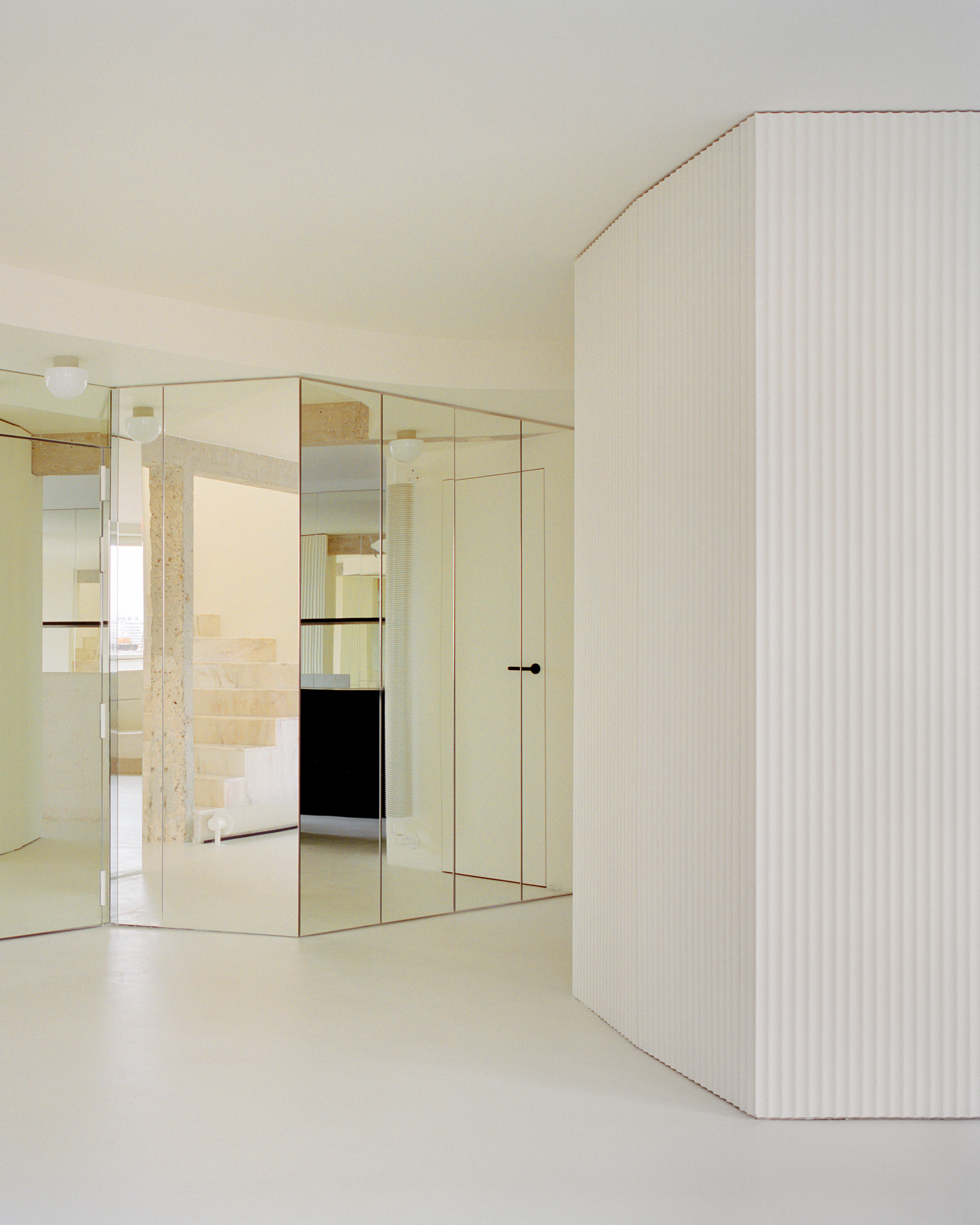 Corner detail of fluted volume and mirrored wall partition with concealed door