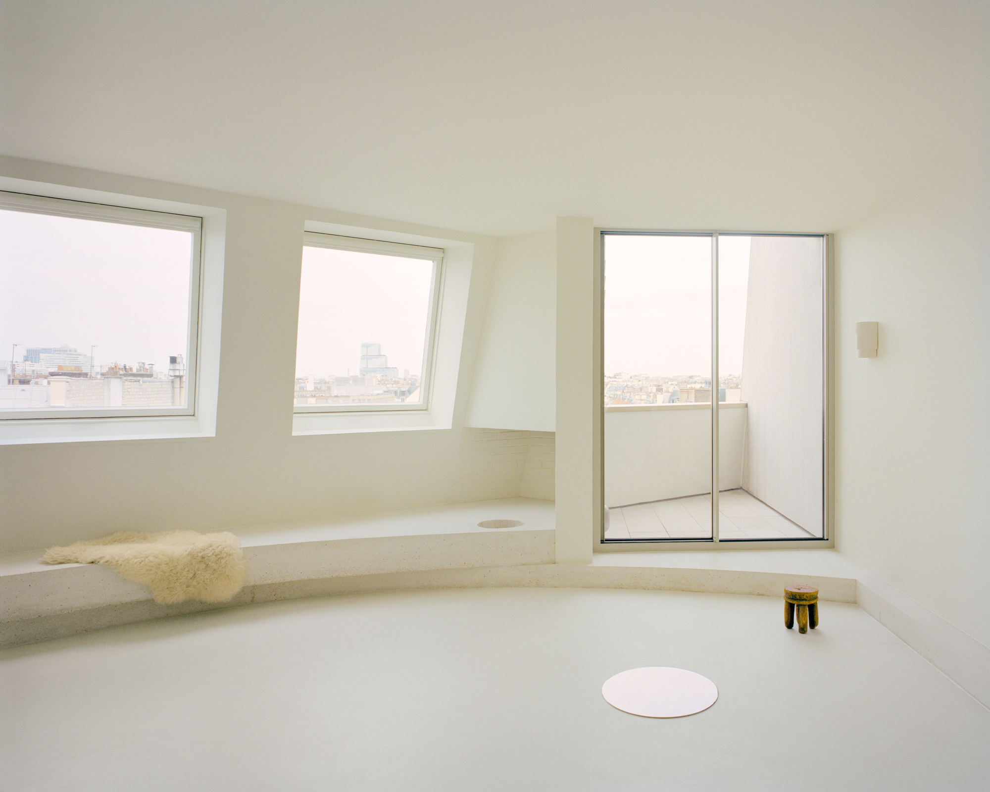 Sunken seating nook with stone bench, sheepskin throw and cityscape windows