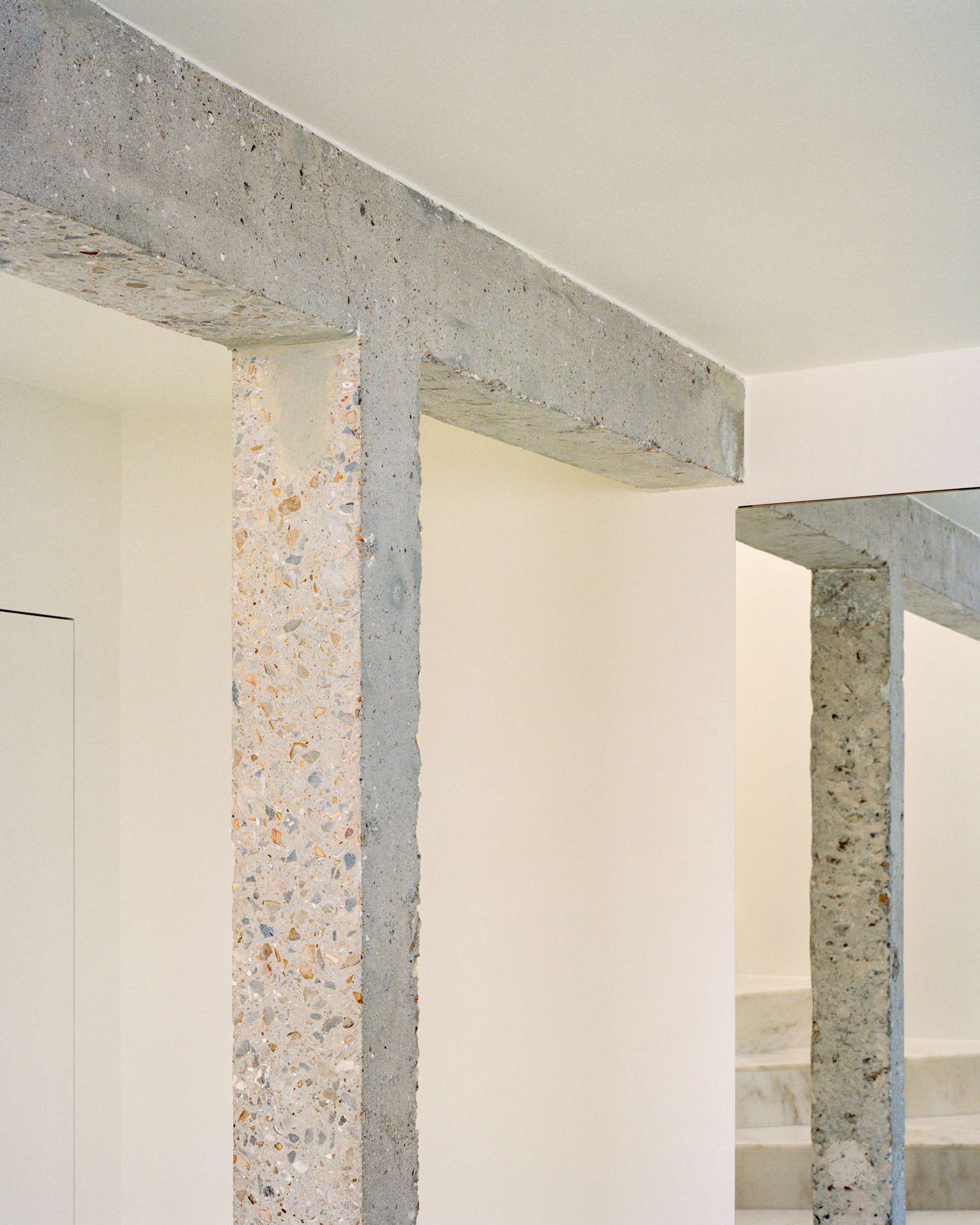 Terrazzo columns and beam junction showing aggregate texture against pale painted walls