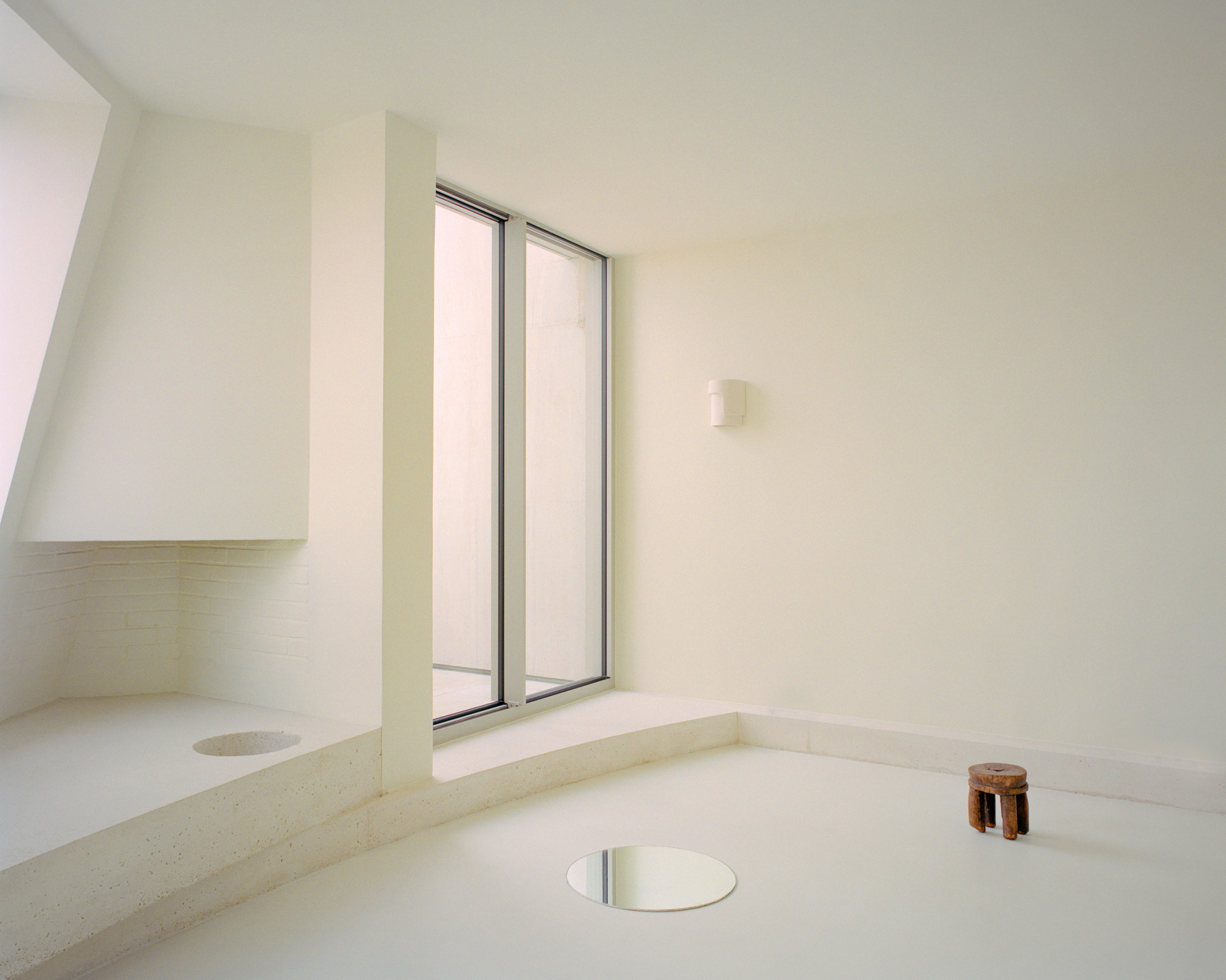 Sunken bath with wide double window and circular floor drain under diffused daylight
