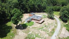 Aerial view of the residence on a rocky clearing surrounded by dense forest canopy