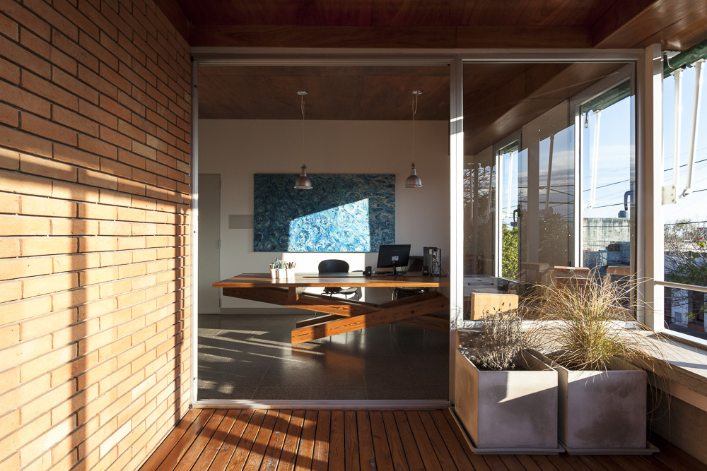 Kitchen with exposed brick wall, pendant lights, and timber deck terrace with planters visible through glass doors