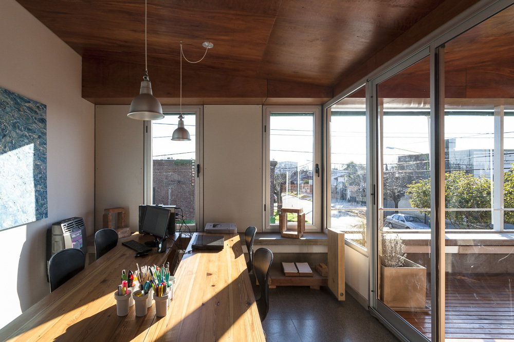 Office workspace with timber ceiling and glazed doors opening to a timber deck in afternoon light