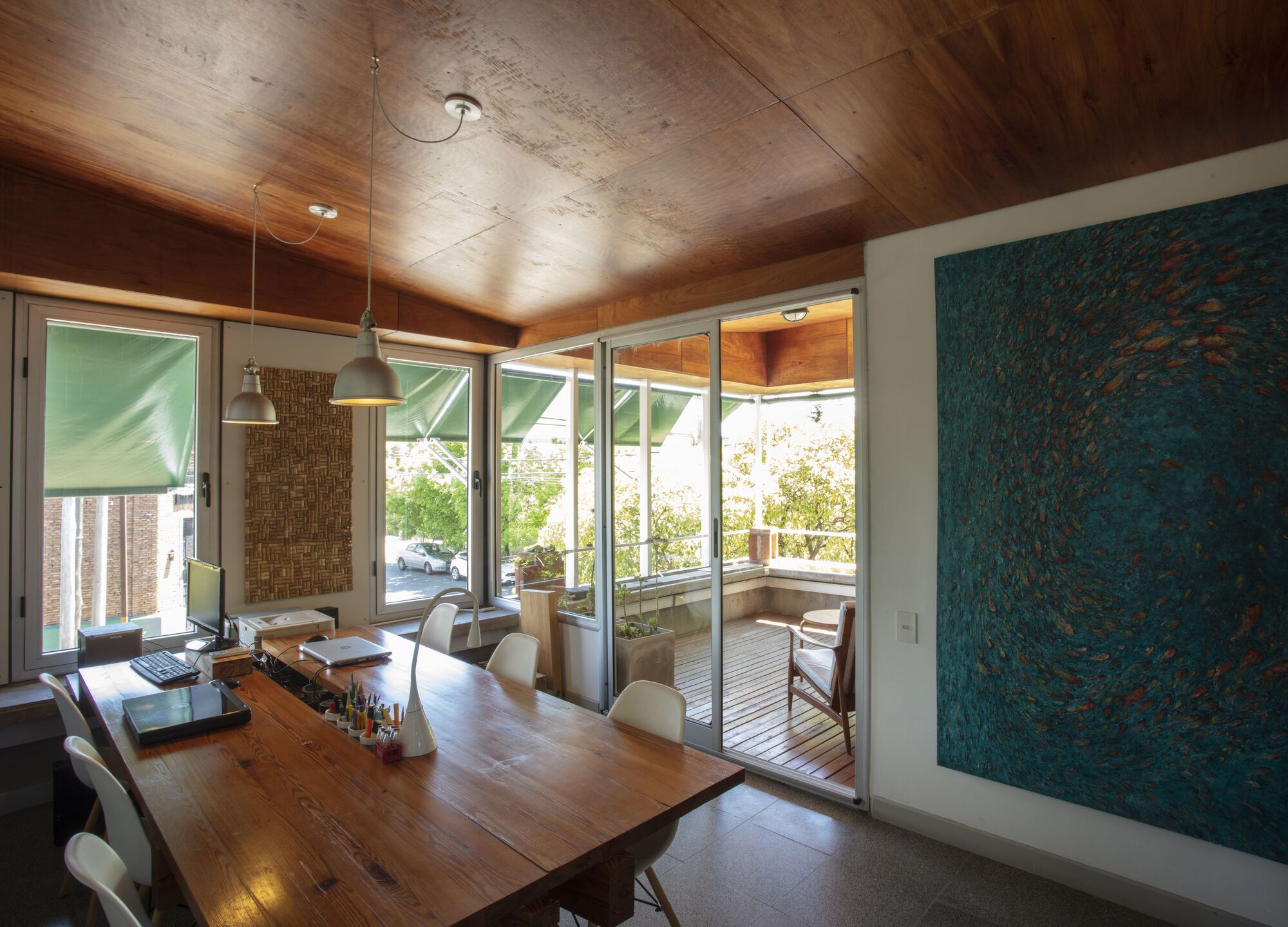 Dining area with angled timber ceiling and sliding glass doors to exterior terrace under bright daylight