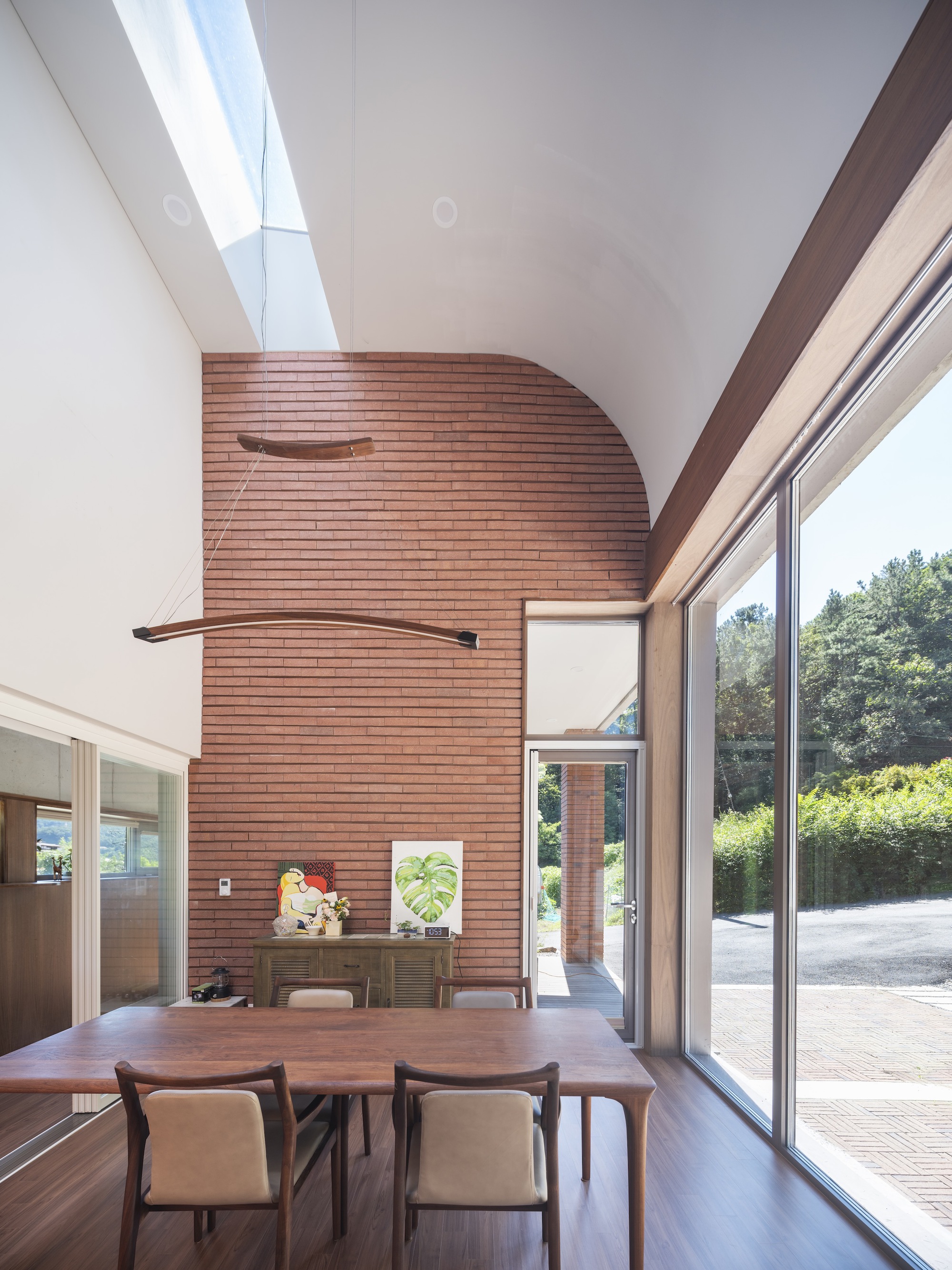 Dining area beneath a curved brick wall with skylight and sliding glass doors to the terrace