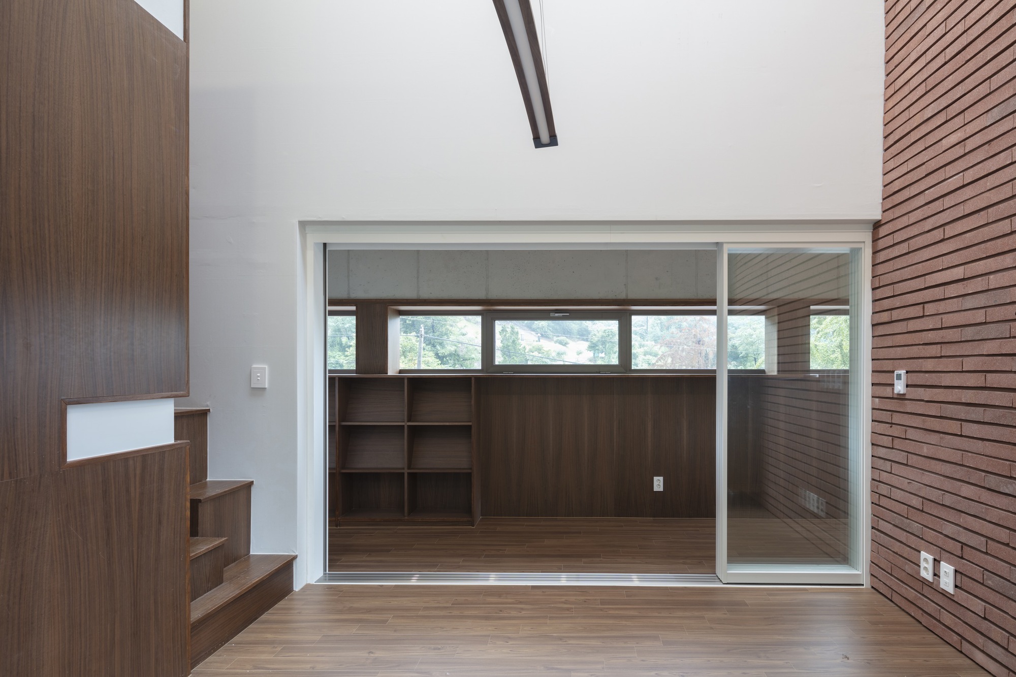 Double-height space with timber stair and glazed sliding partition to adjacent room with built-in shelving