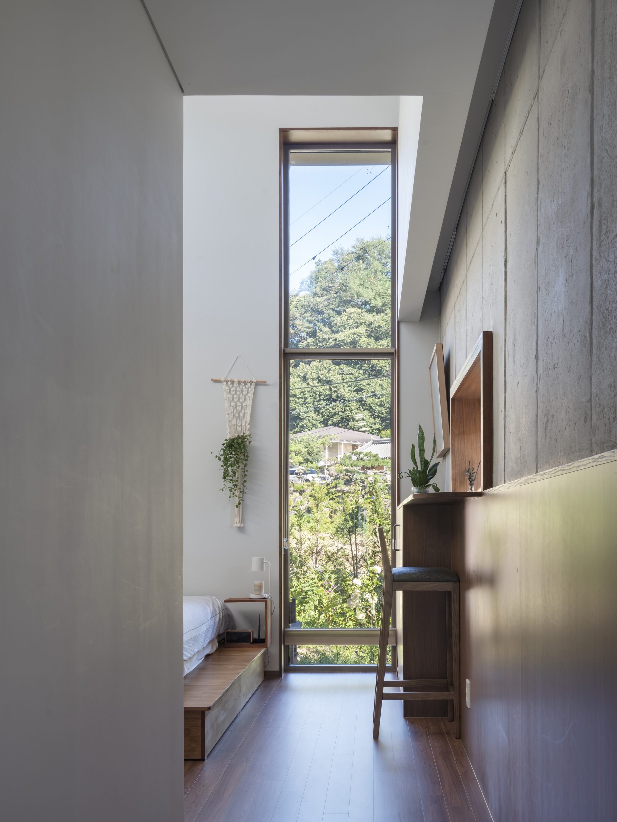 Narrow hallway with tall vertical window framing views of hillside foliage and overhead power lines