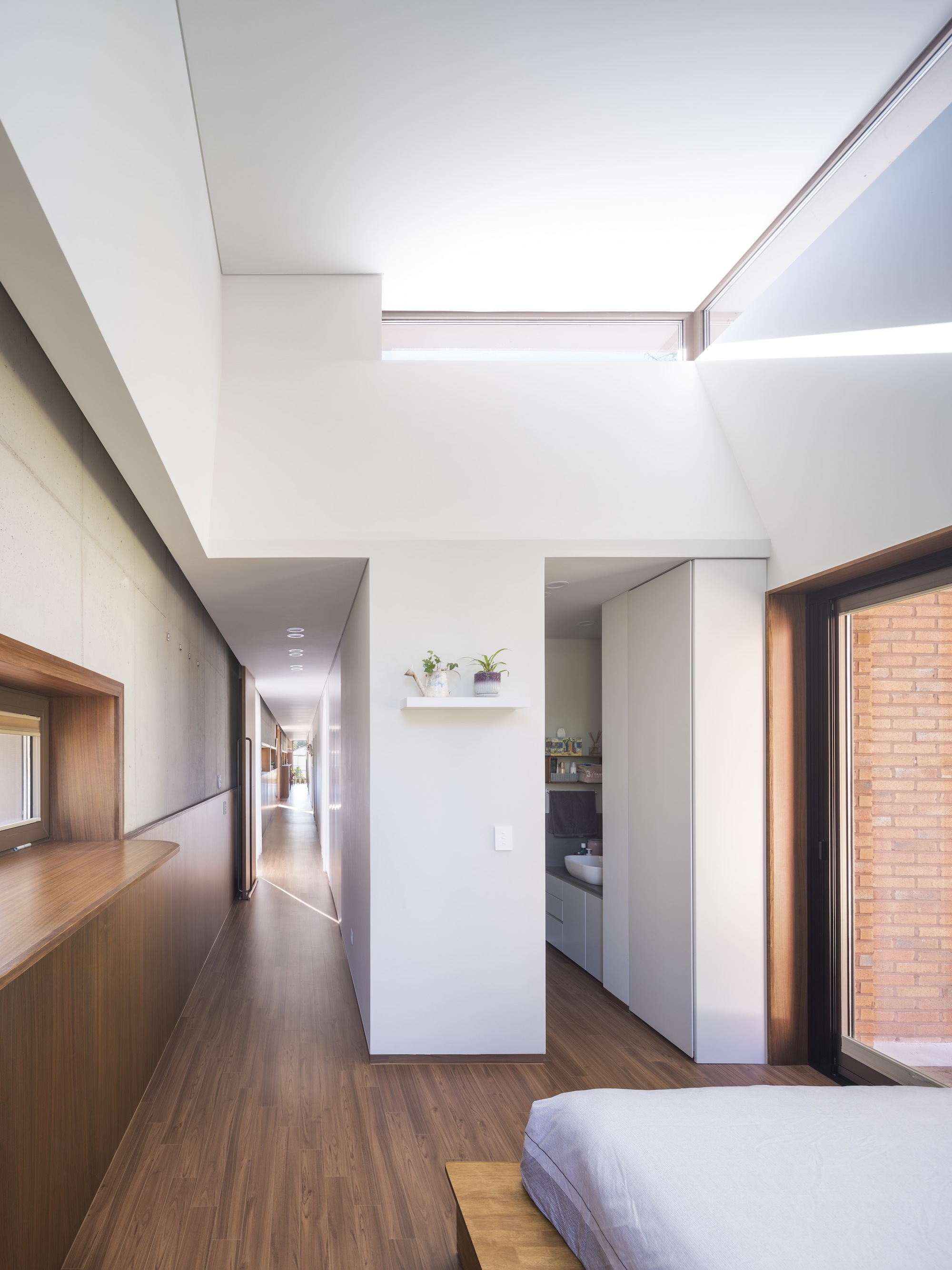 Open bedroom plan with clerestory slot and corridor leading past concrete walls to adjacent spaces