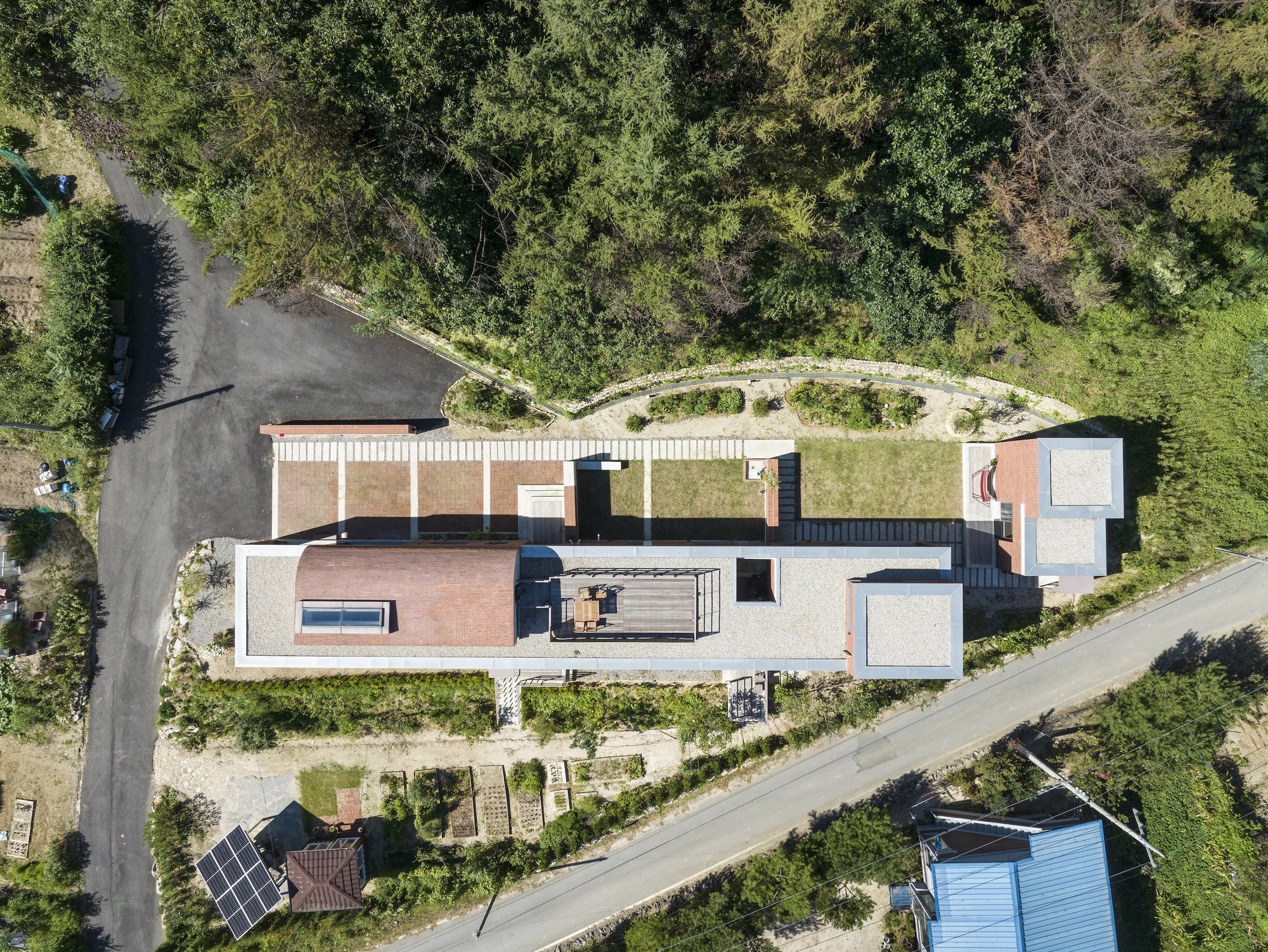 Drone view showing the curved green roof wrapping around the stepped volumes and terraces