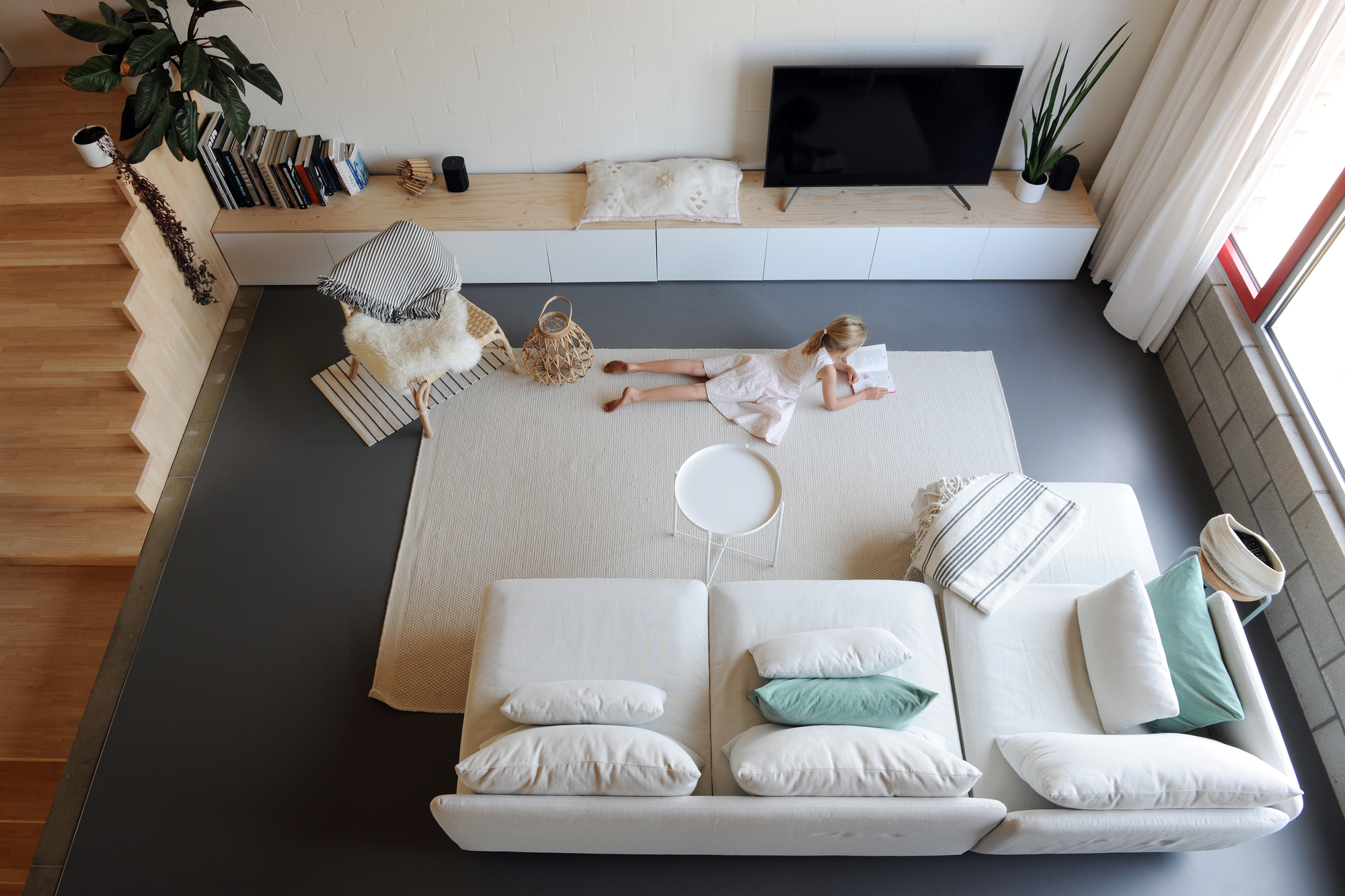 Overhead view of living room showing child playing on rug beside built-in media console