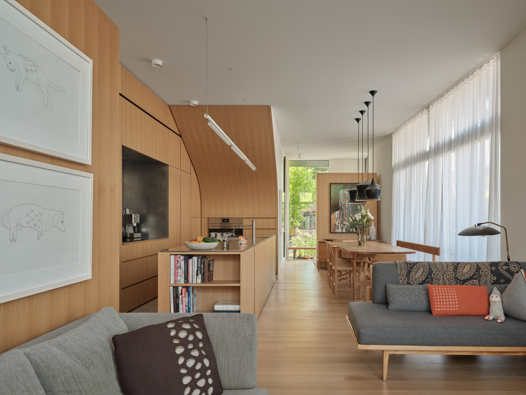 Open plan living space with bamboo cabinetry and sheer curtains filtering afternoon light