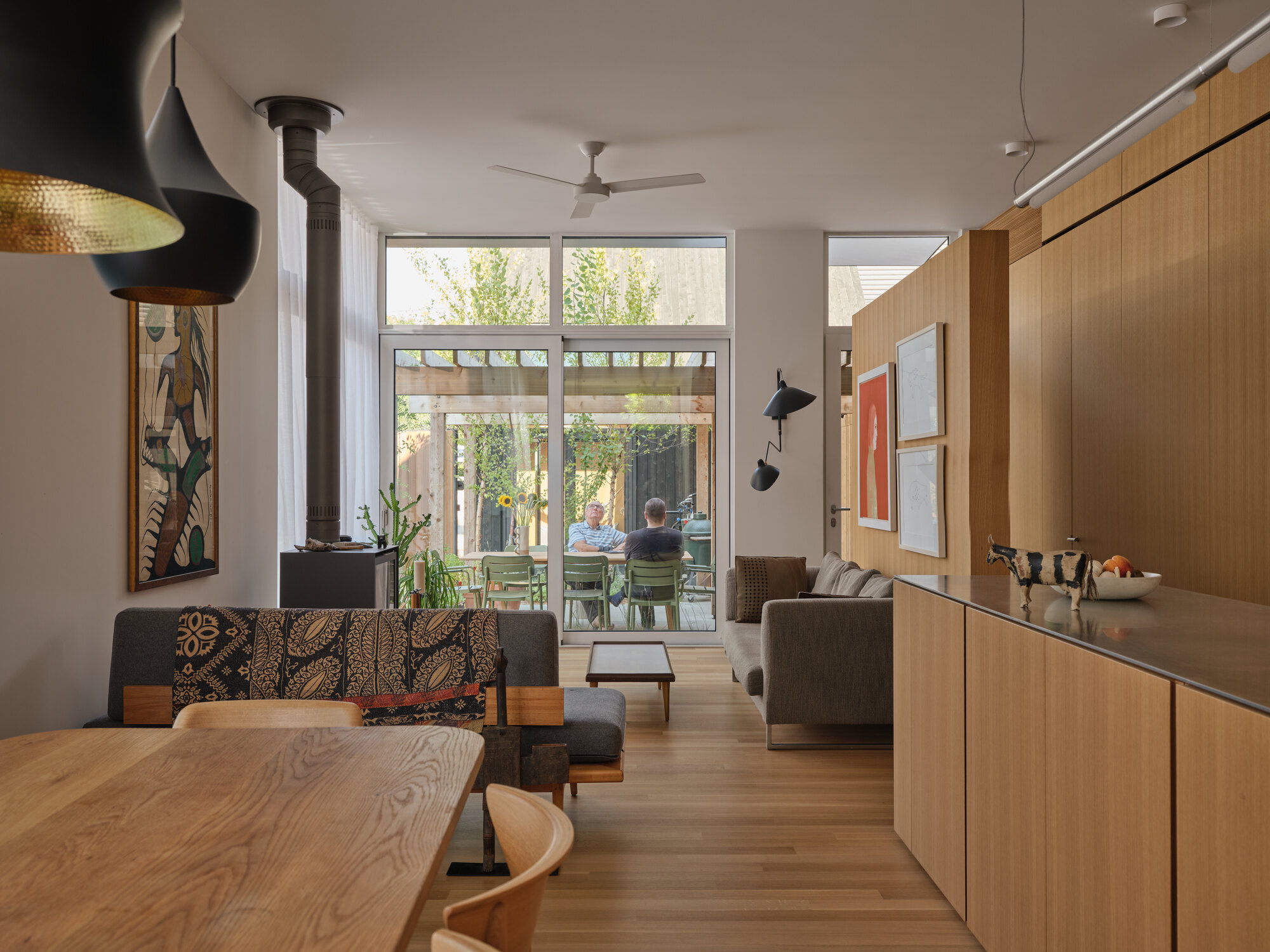 Open plan living space with wood-burning stove, timber millwork, and glazed doors to rear courtyard