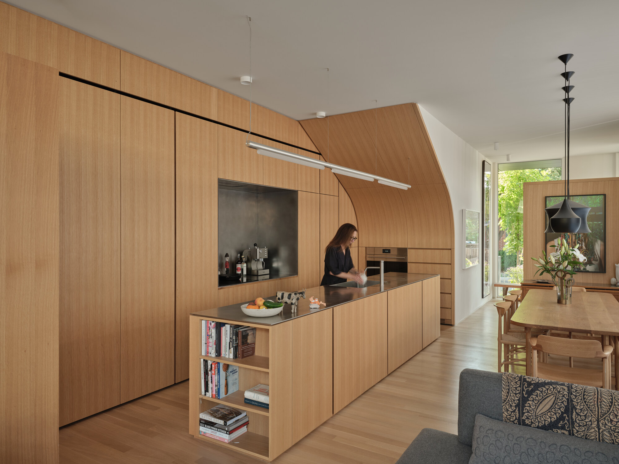 Kitchen island with integrated bookshelf and cantilevered wood volume housing appliances