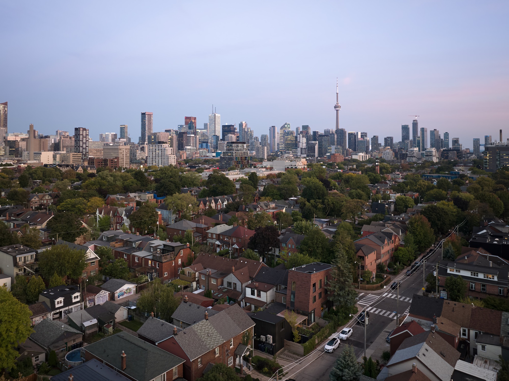 Aerial view of residential neighborhood with skyline towers visible under pink evening sky