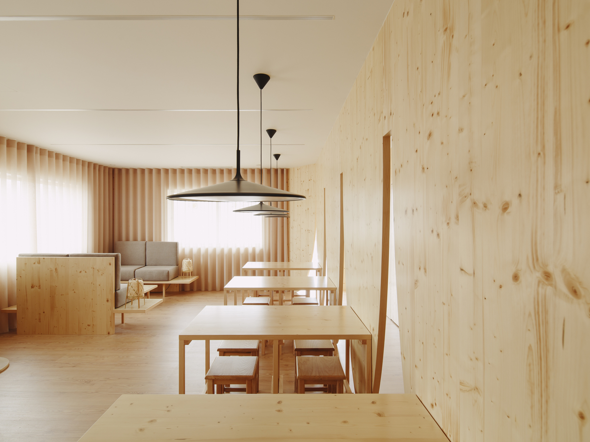 Open living and dining space with timber slat curtain wall filtering daylight