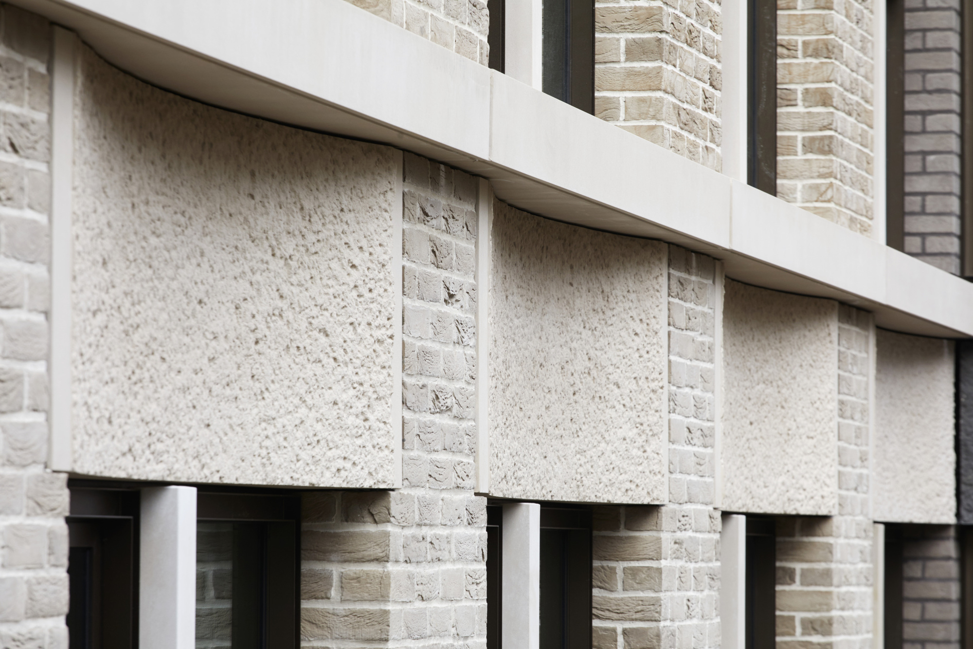 Close-up of precast concrete lintels and spandrel panels alternating with pale brick coursing