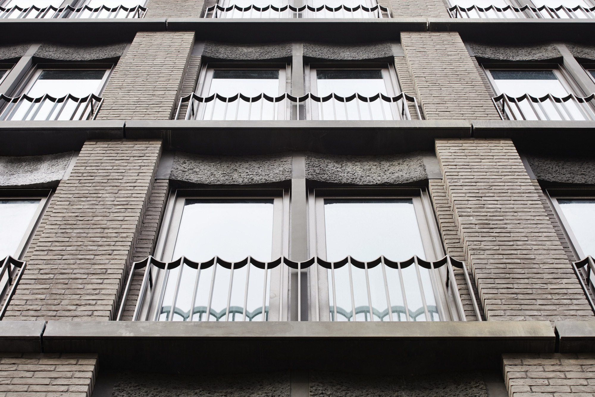 Facade detail showing scalloped metal awnings above windows with textured brick piers