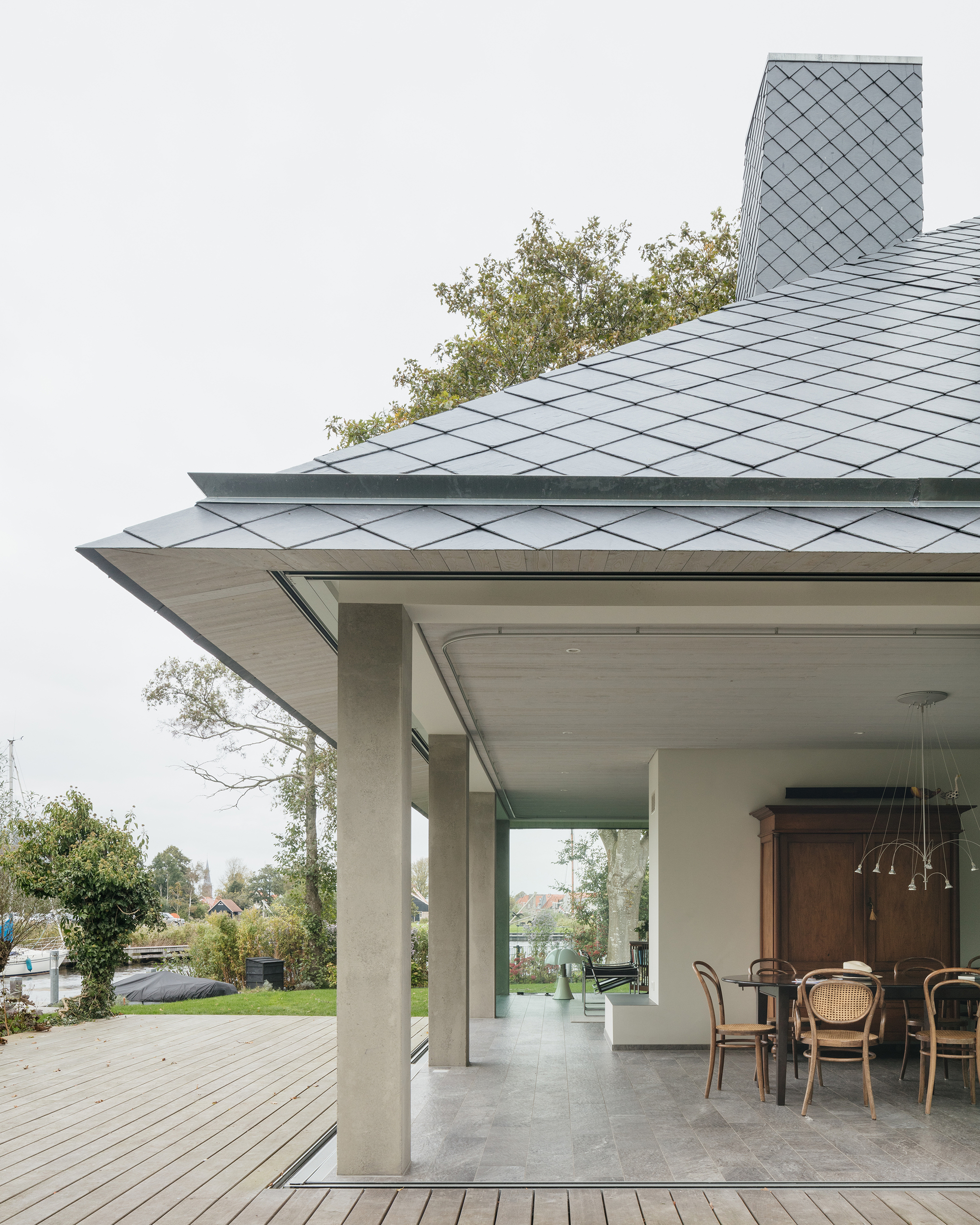 Detail of the overhanging roof eave with diamond-pattern zinc shingles above concrete columns
