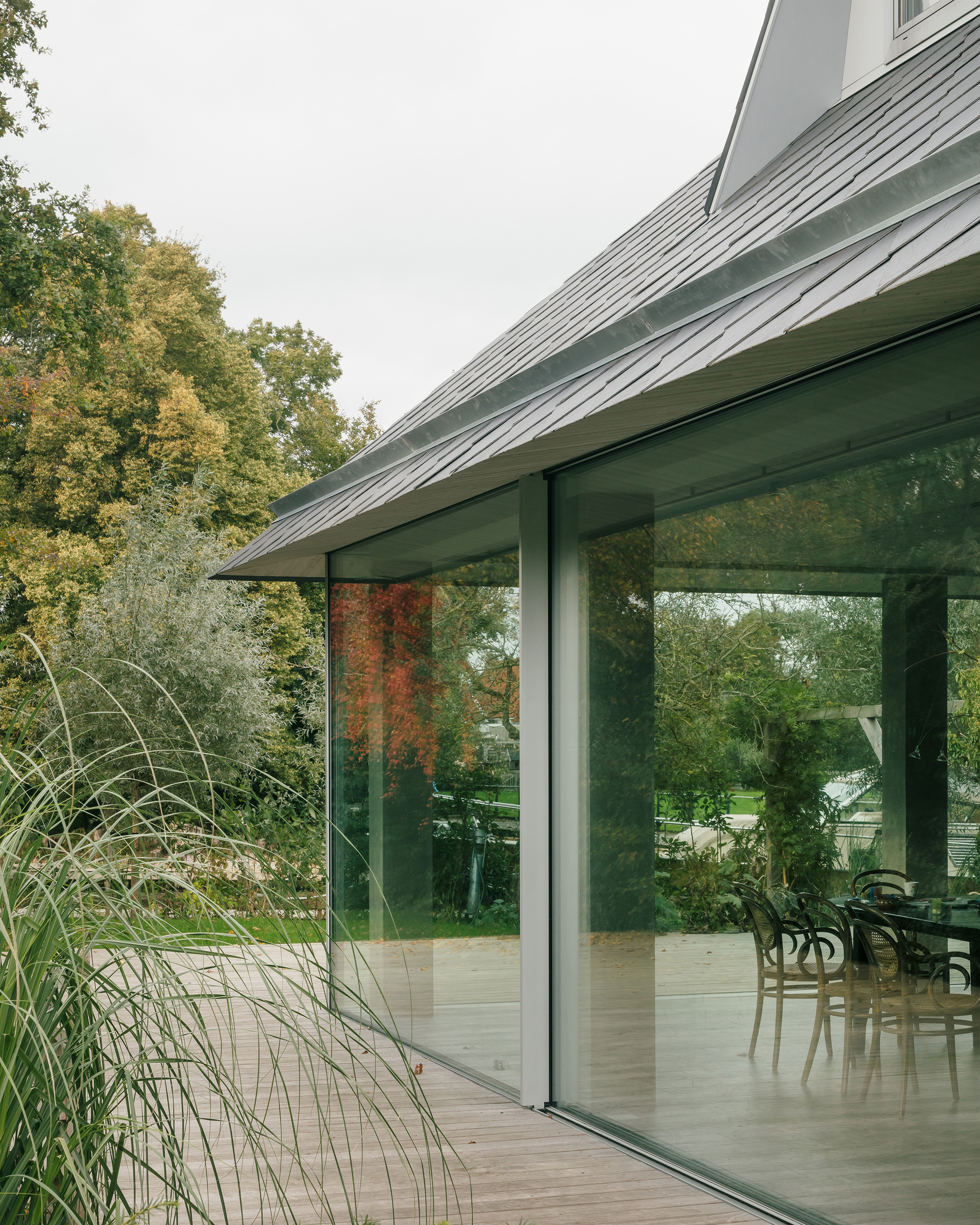 Corner of the glass extension with ornamental grasses beside the sliding doors