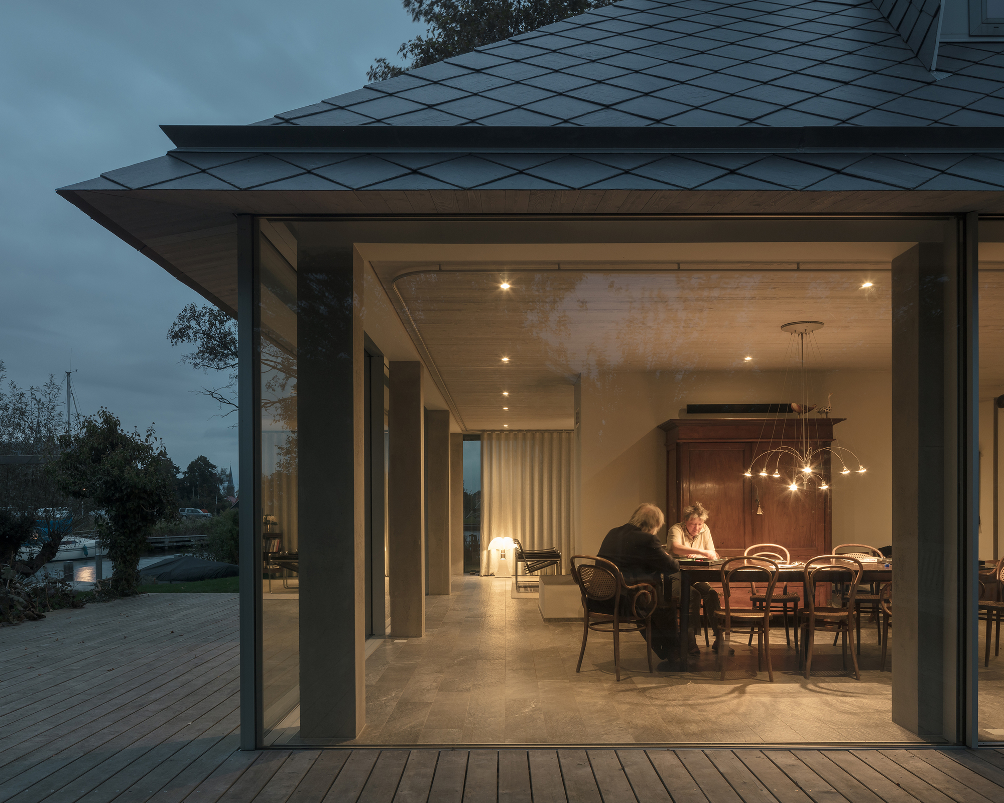 Open glass doors framing a dining room with pendant lighting at dusk