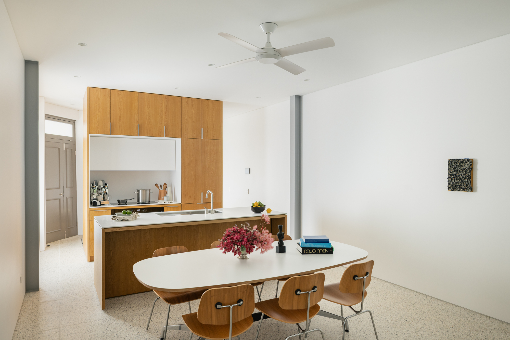 Open dining area with oak island kitchen and white oval table beneath ceiling fan