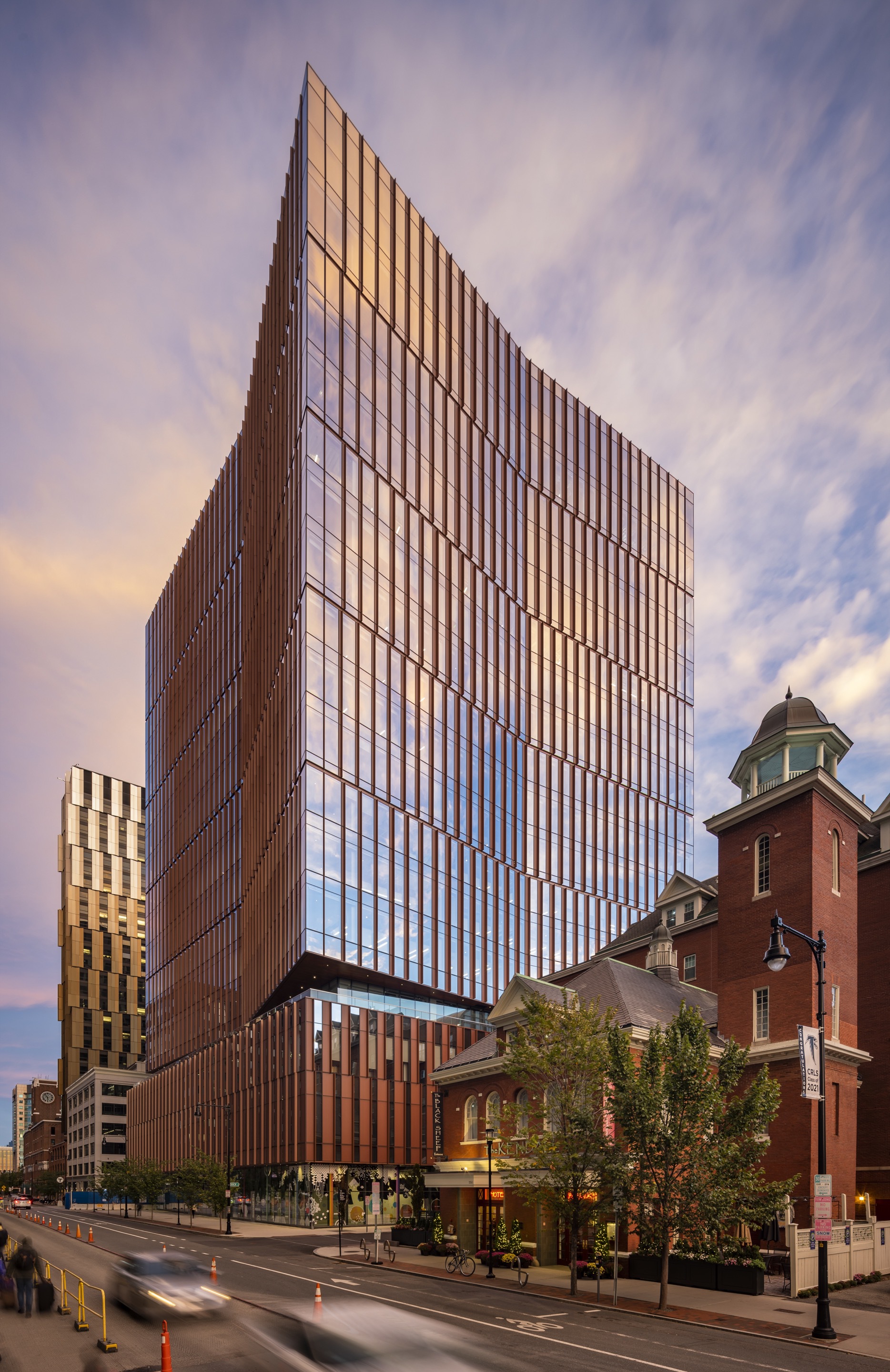 Street view of the tower at sunset beside a historic red brick building with cupola