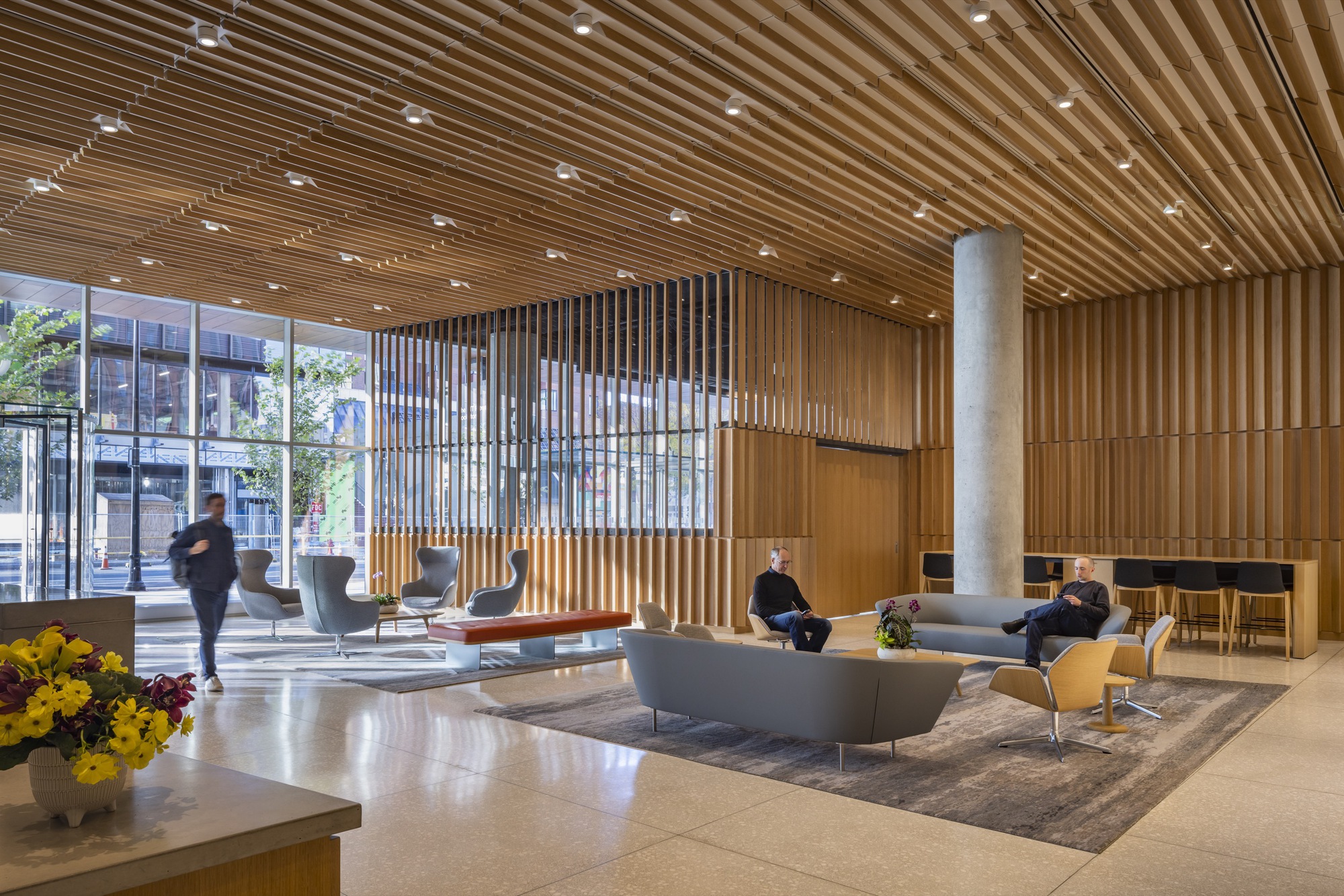 Lobby interior with timber slat ceiling and vertical screen dividing the lounge seating from the glazed street entrance