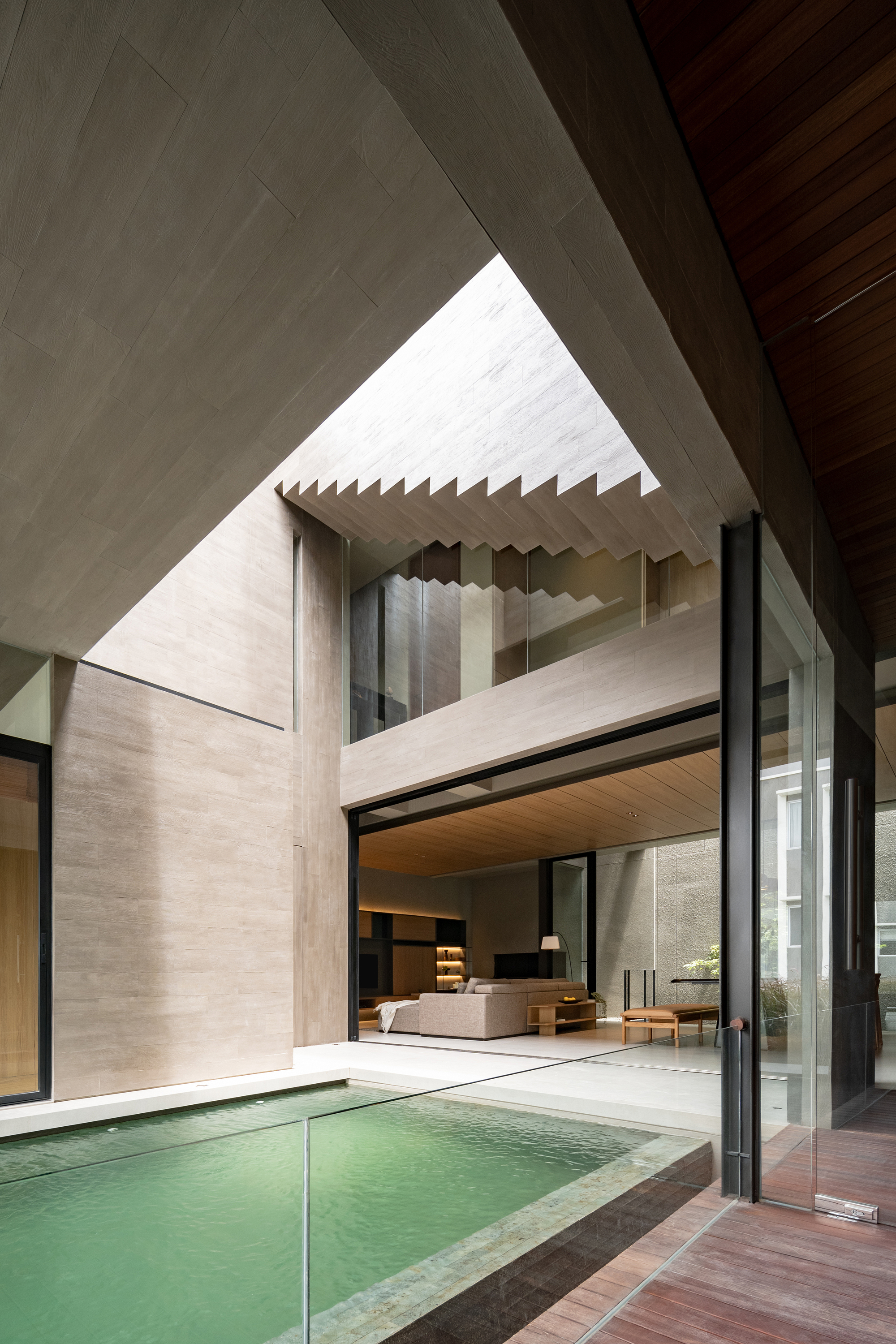 Central courtyard with triangular skylight above floating concrete staircase and shallow pool