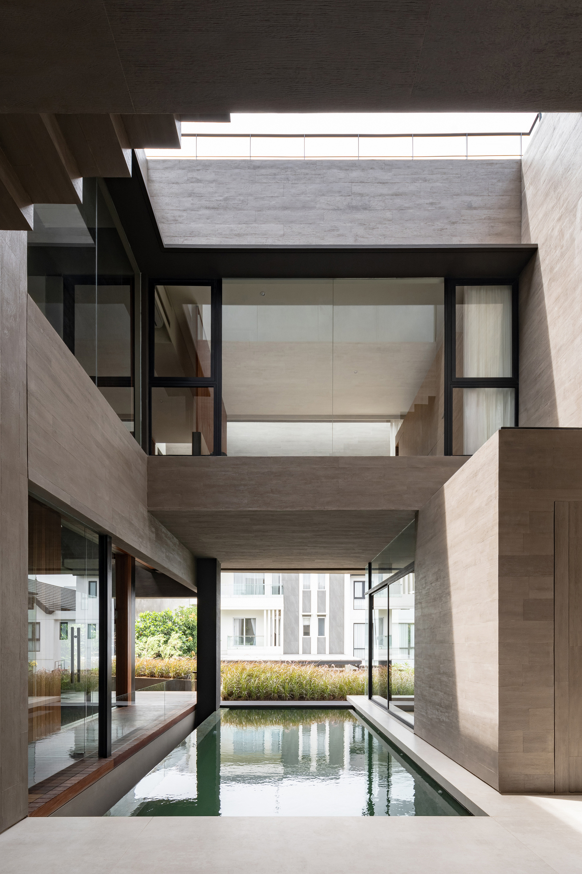 Double-height courtyard space with lap pool and concrete walls framing views of adjacent residential buildings
