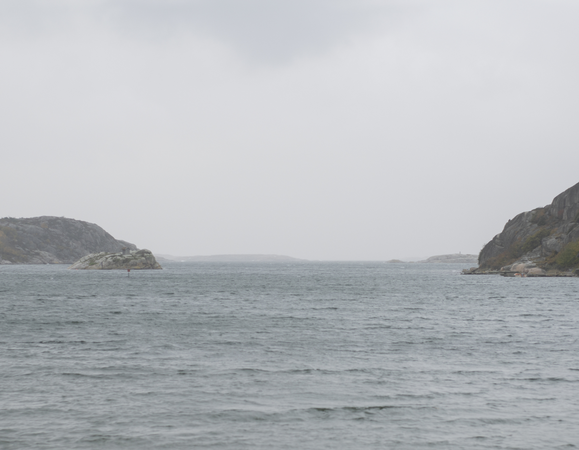 View across grey water toward rocky islands under overcast sky