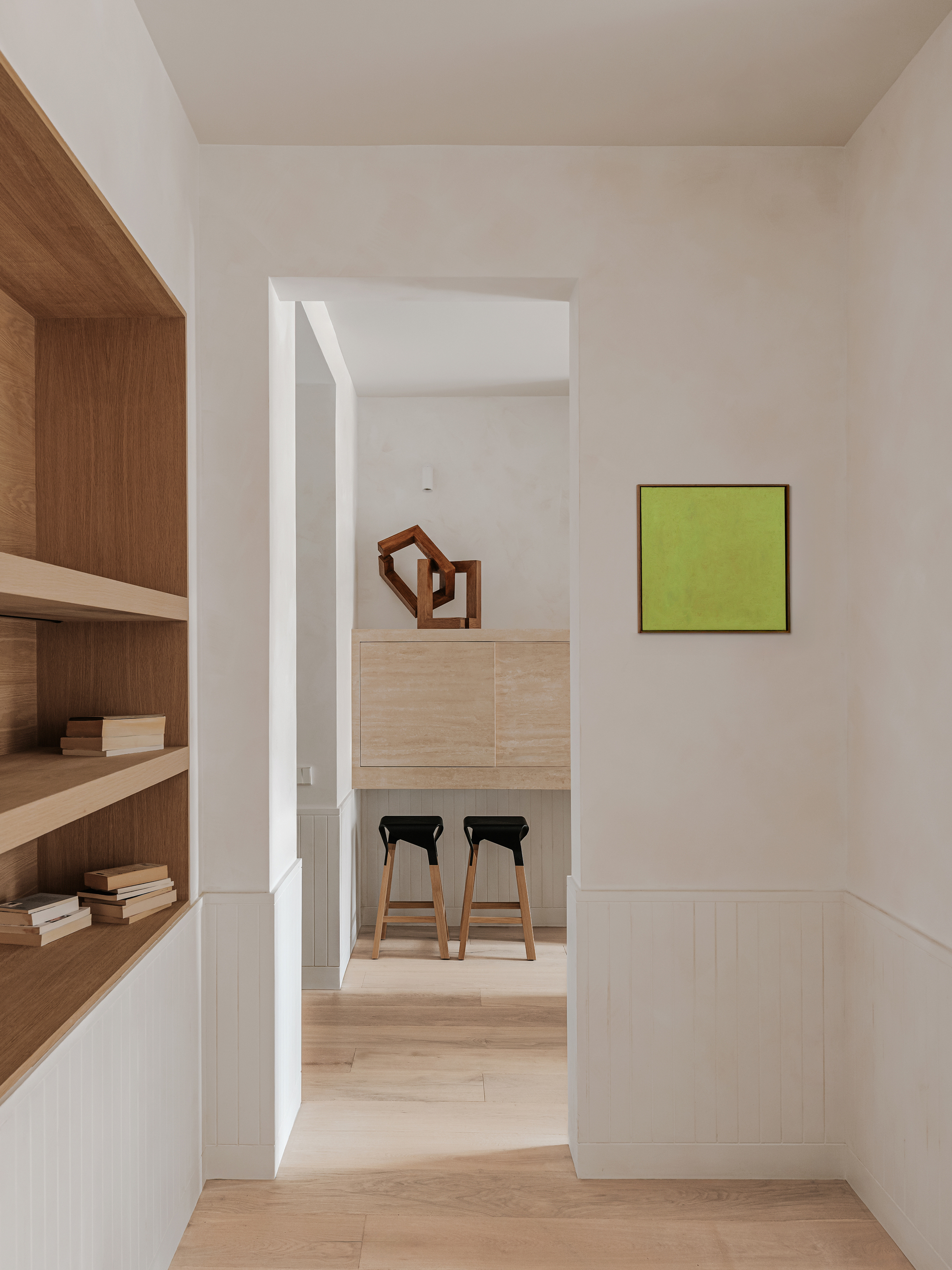 View through doorway to kitchen island with two bar stools and chartreuse painting on wall