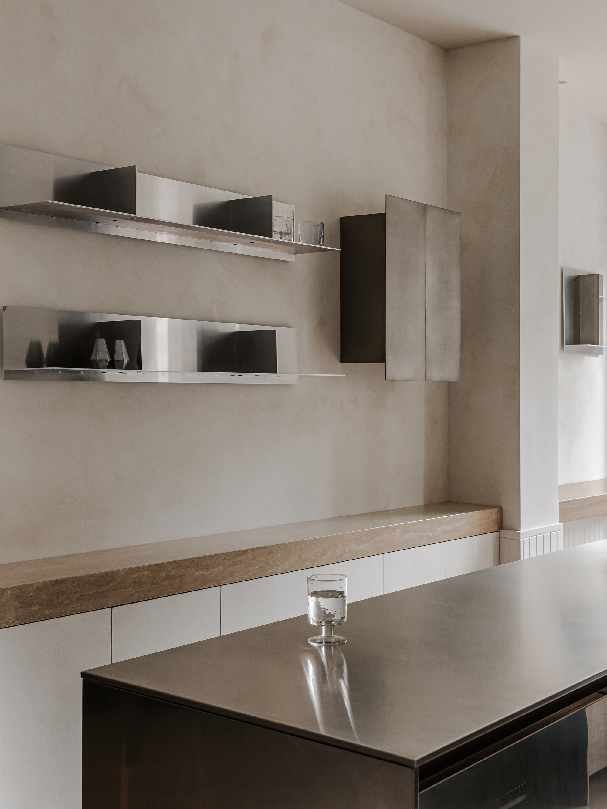 Stainless steel floating shelves displaying ceramics above a wood and white lacquered counter